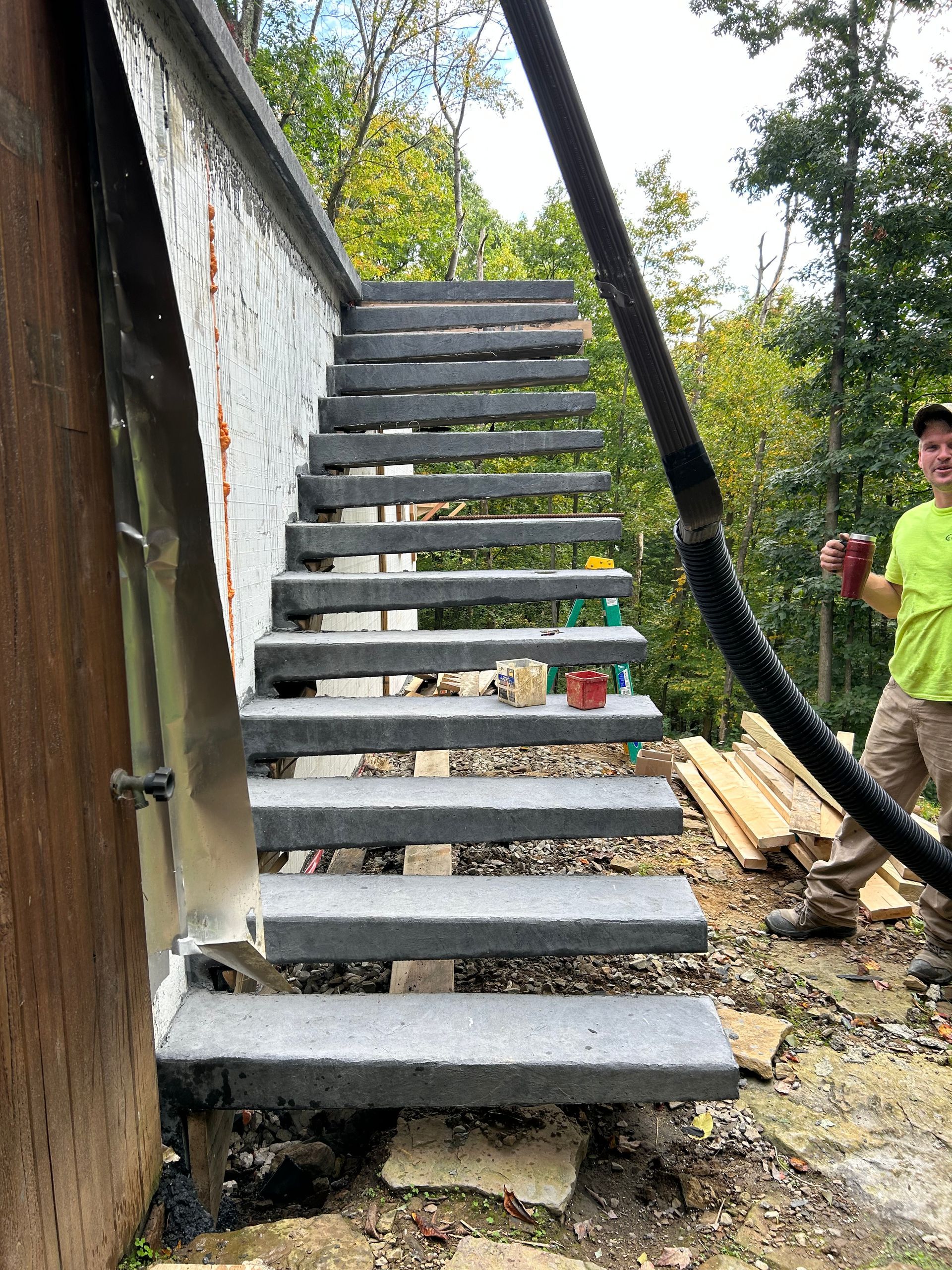 A man in a yellow shirt is standing next to a set of stairs.