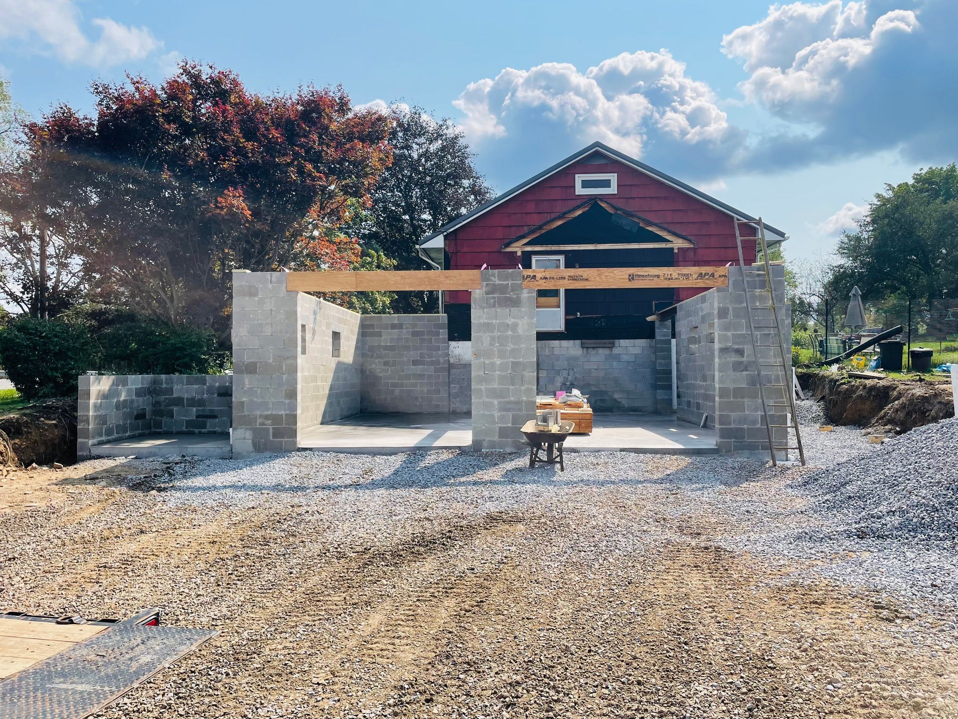 A brick building is being built in front of a red barn.