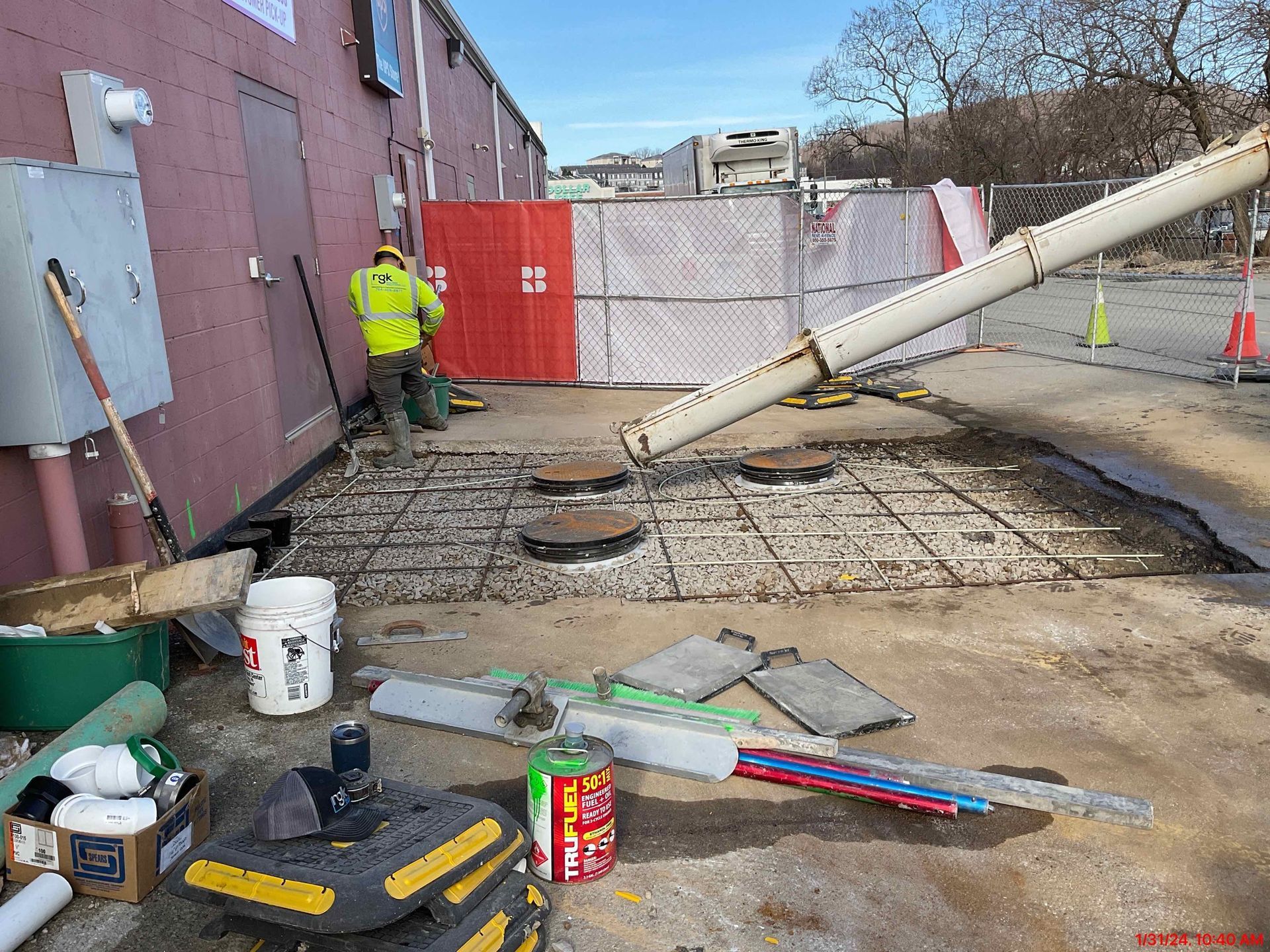 A man in a yellow vest is standing in front of a building.