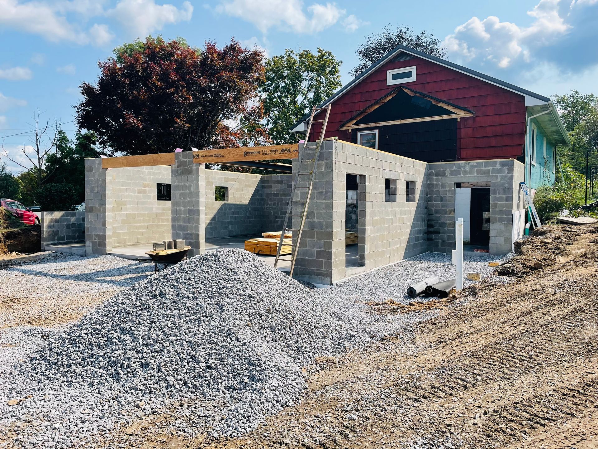 A brick building is being built in front of a red barn.