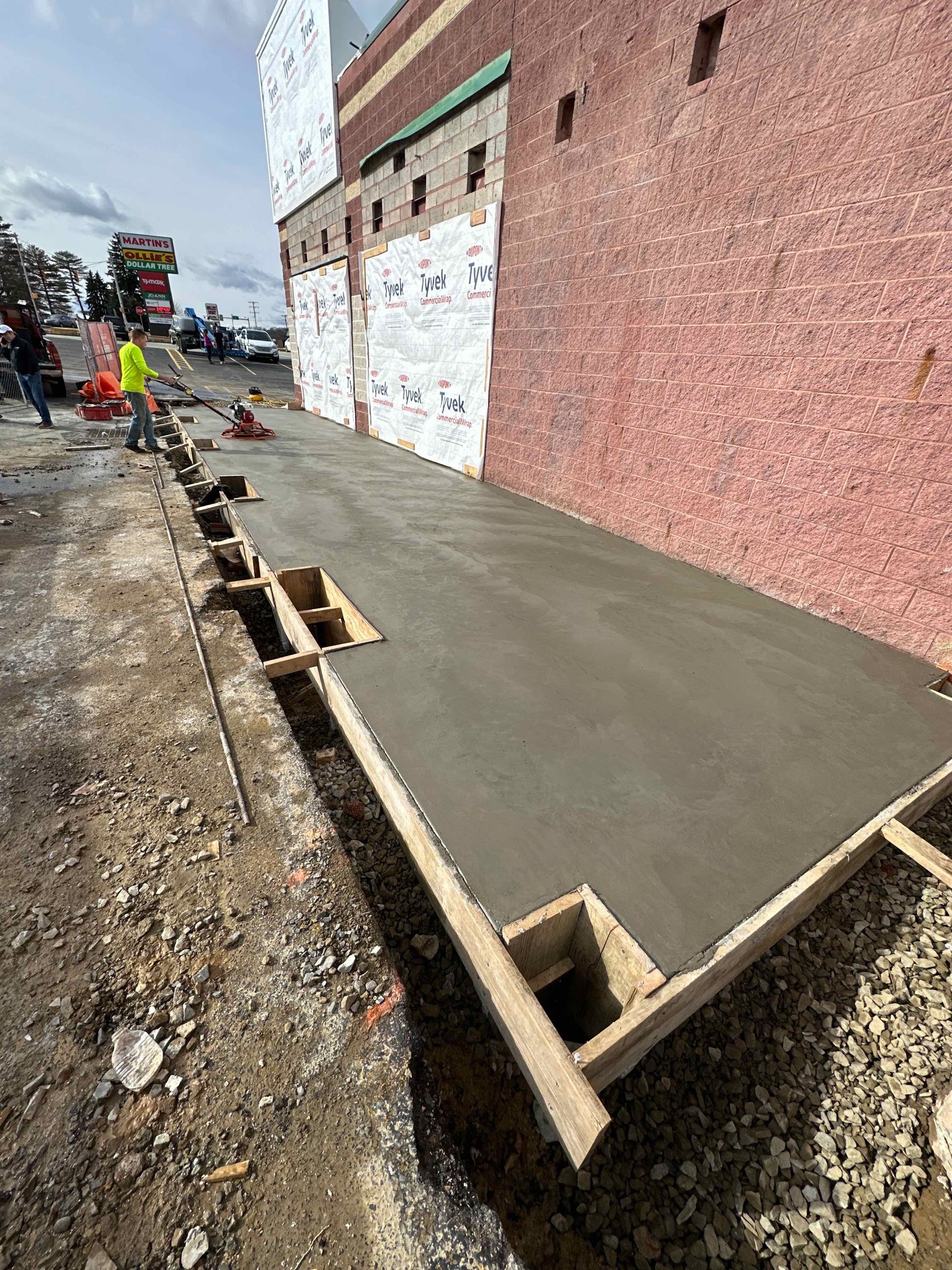 A sidewalk is being built in front of a brick building.
