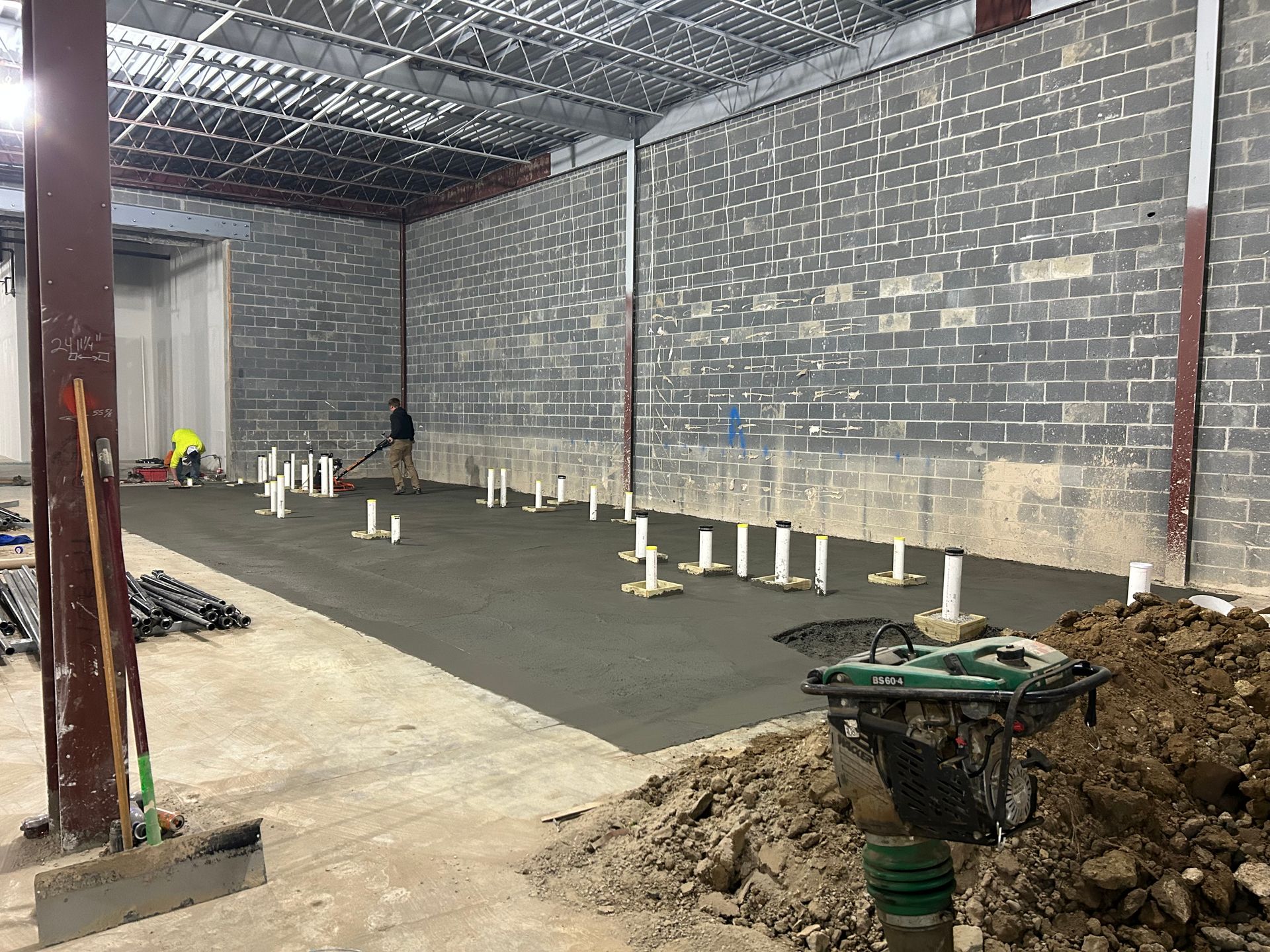 A concrete floor is being poured in a building under construction.