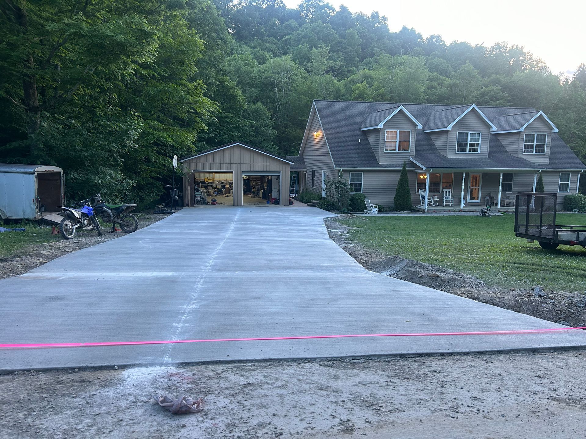 A concrete driveway is being built in front of a large house.