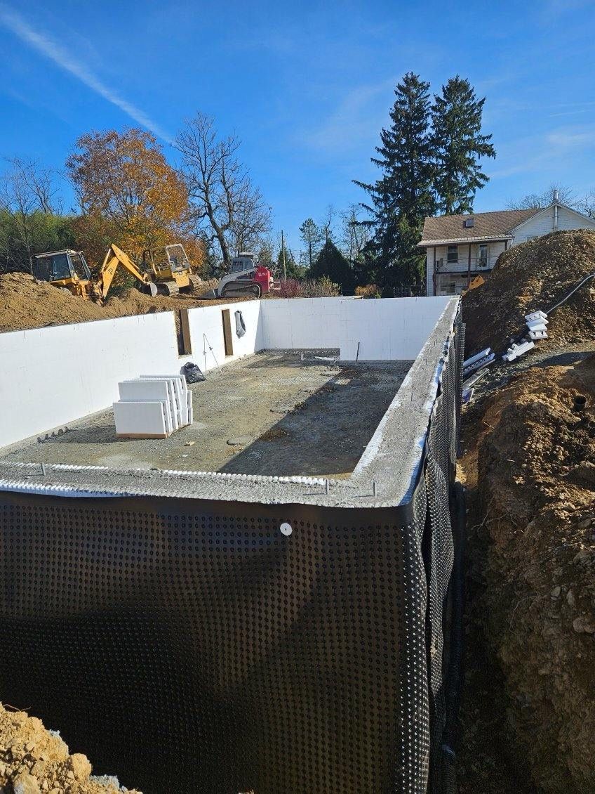 A large swimming pool is being built in the middle of a dirt field.