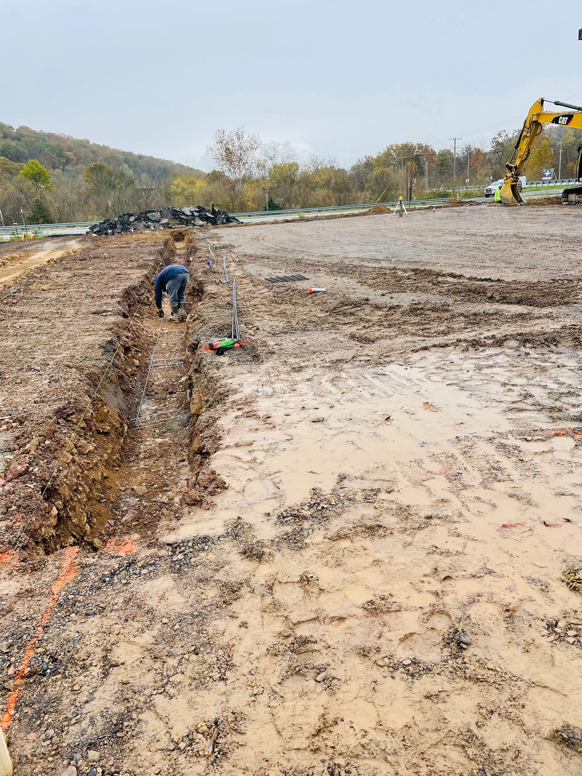 A man is digging a hole in the dirt in a muddy field.