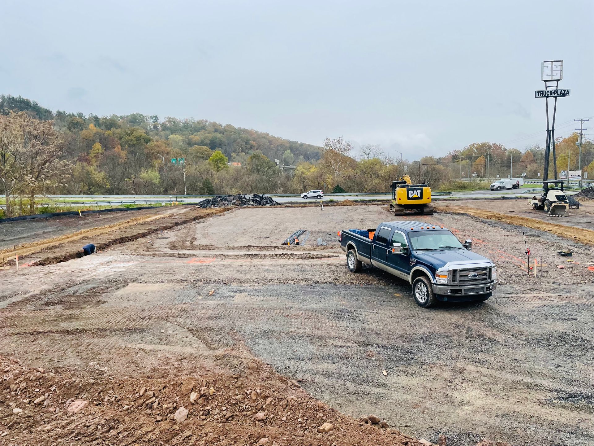 A blue truck is parked in a dirt lot at a construction site.
