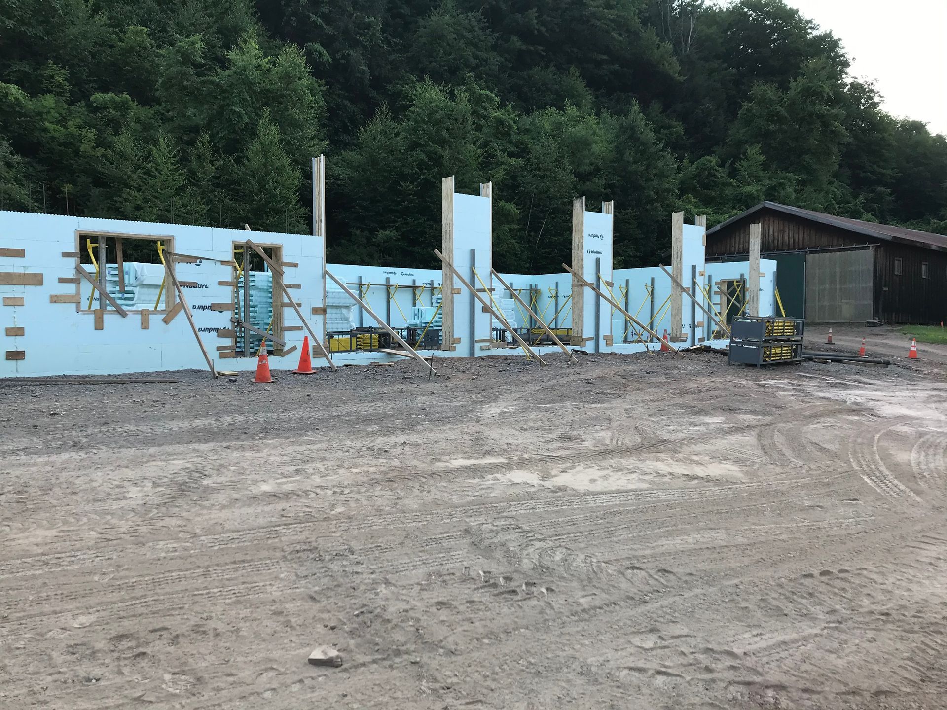 A building is being built in a dirt field with trees in the background.