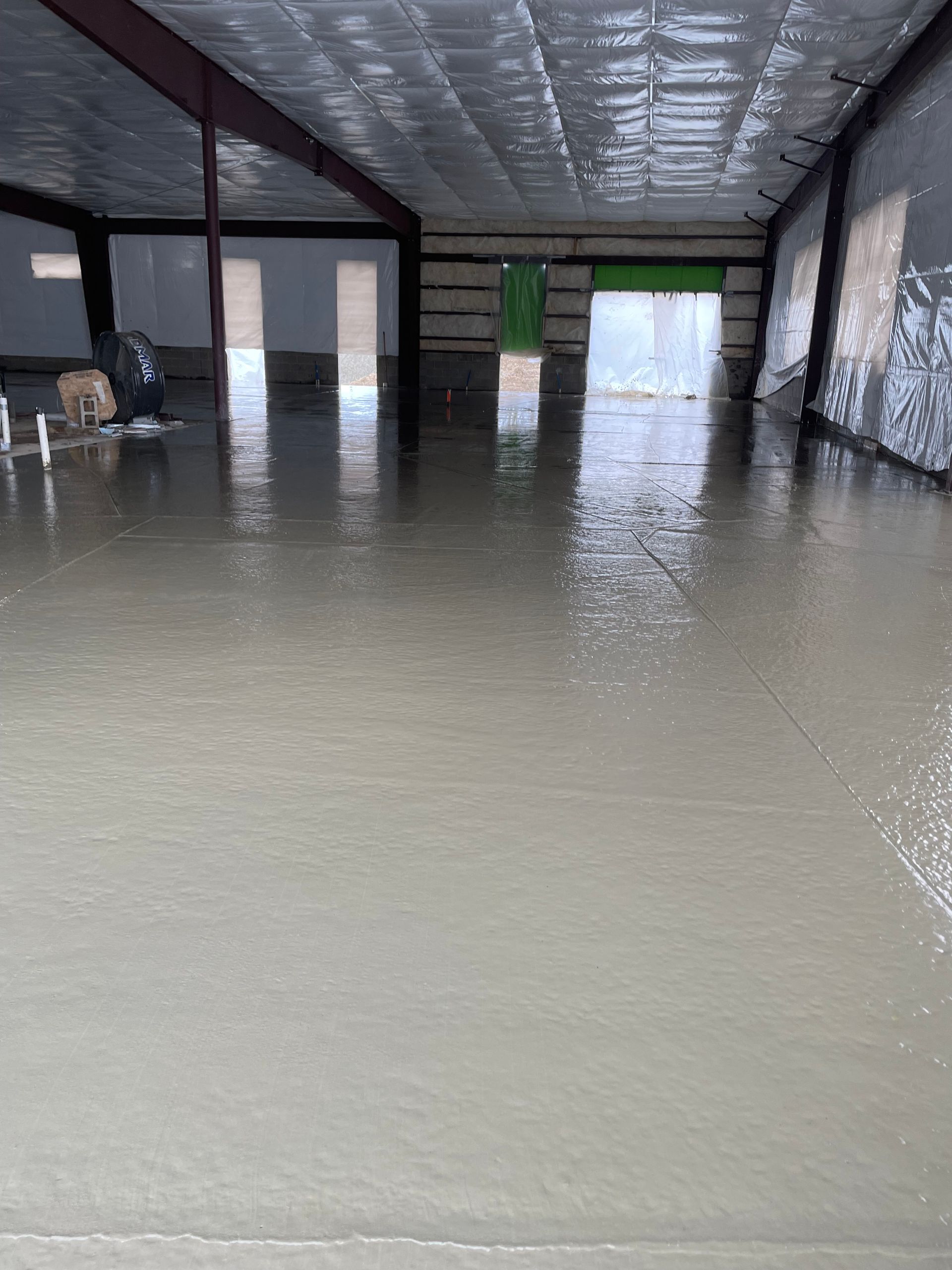 A large room with a concrete floor and a green door.