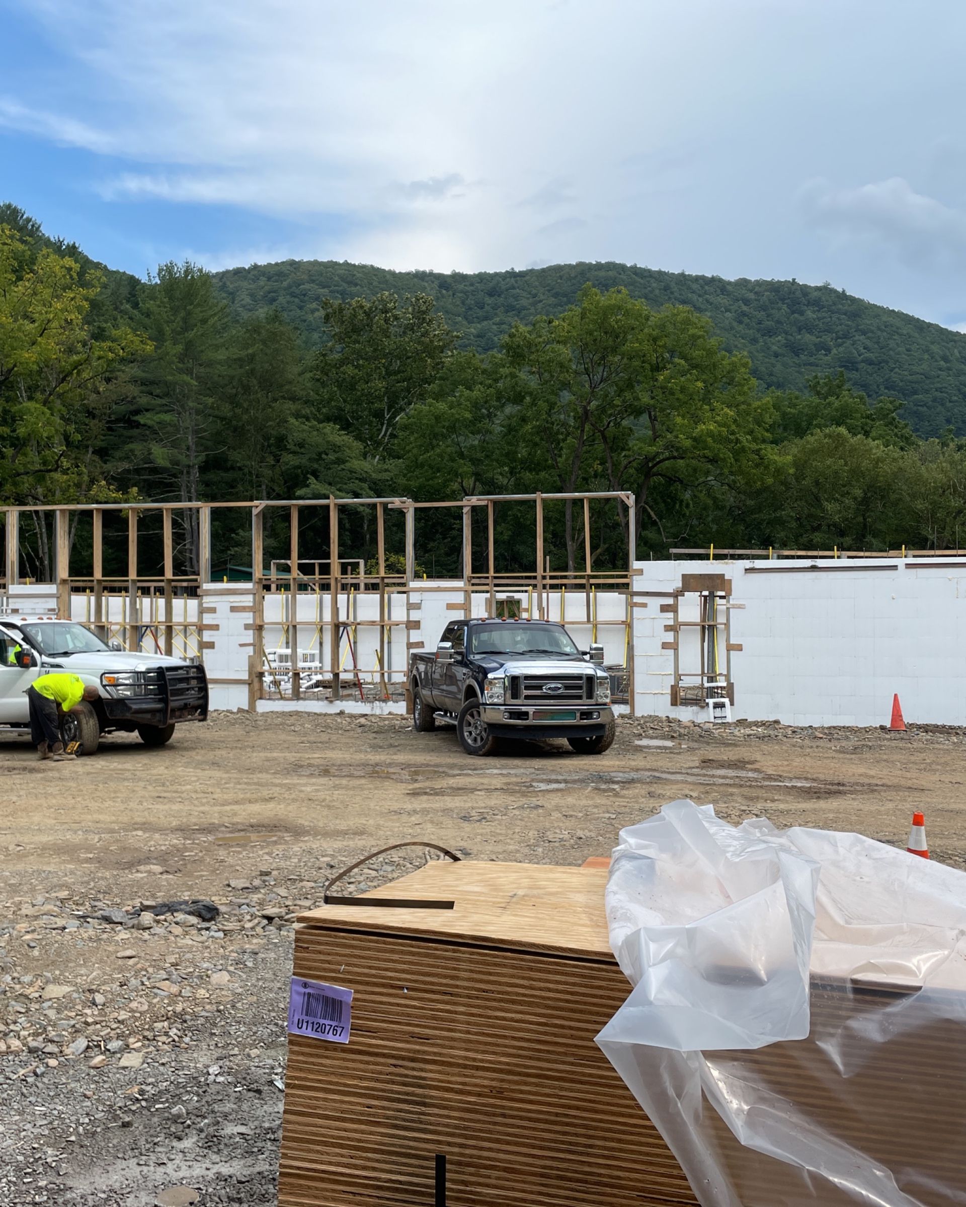 A construction site with trucks parked in front of a building under construction.