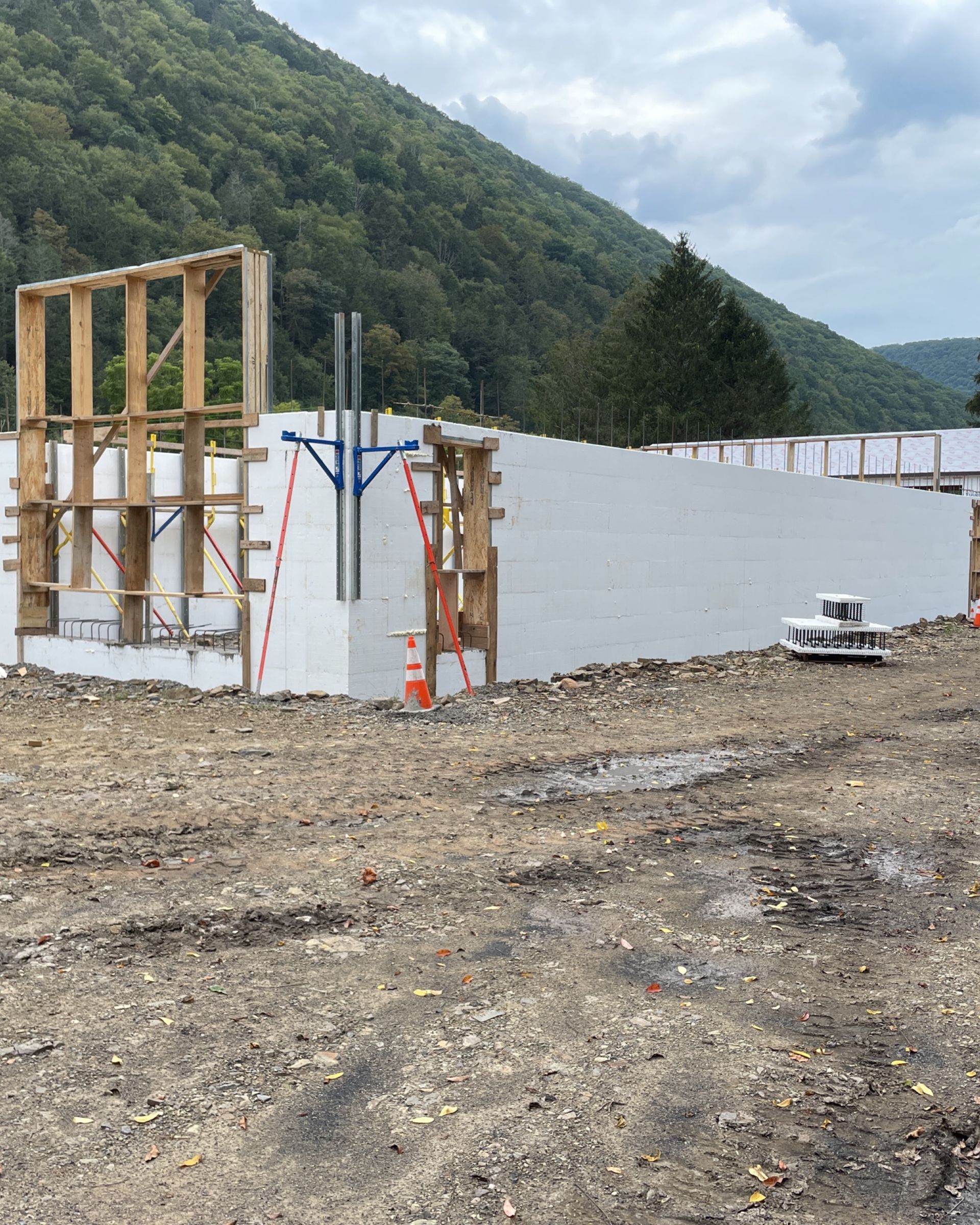 A large white wall is being built in the middle of a dirt field.