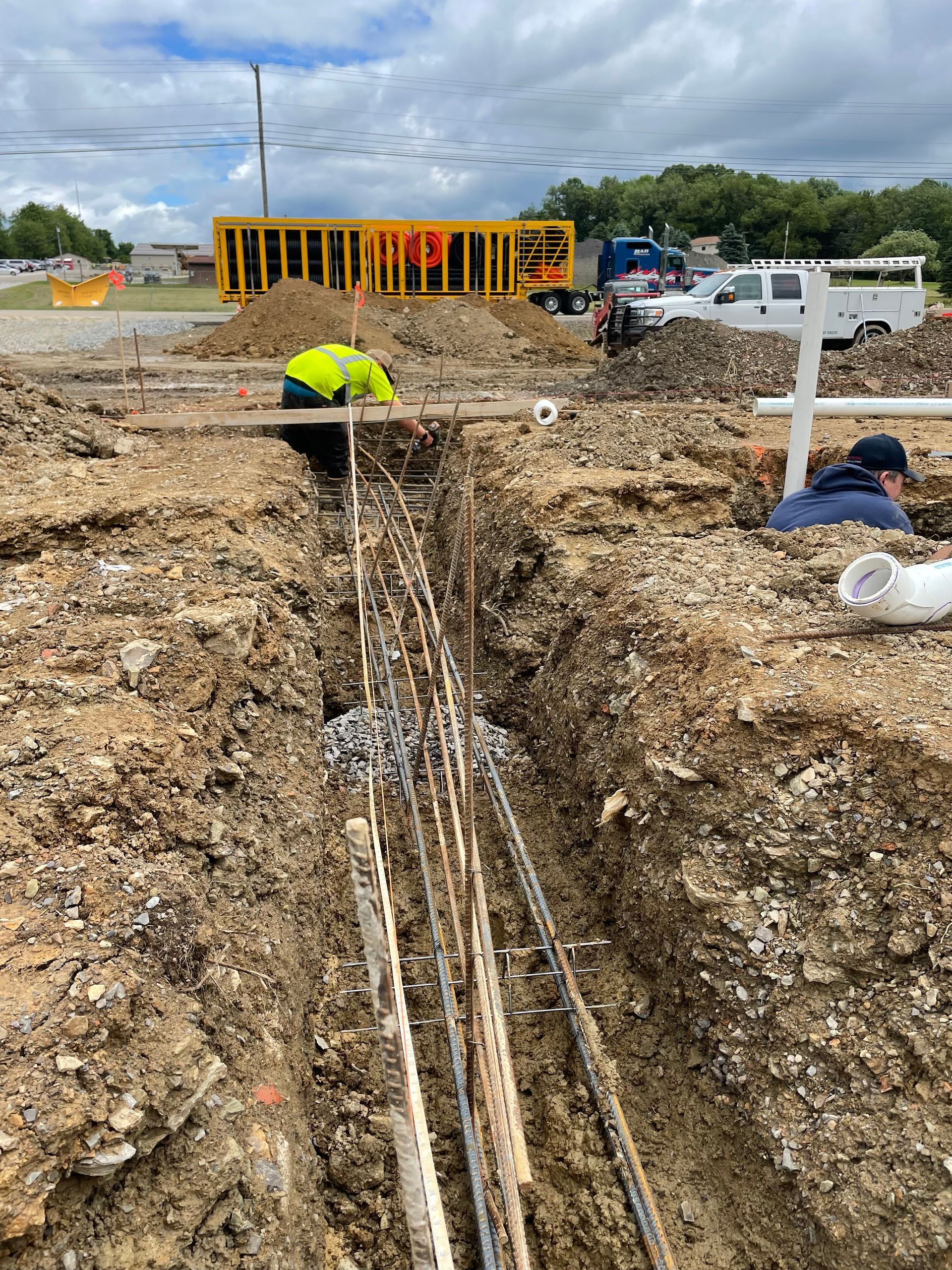 A construction worker is digging a trench in the dirt.