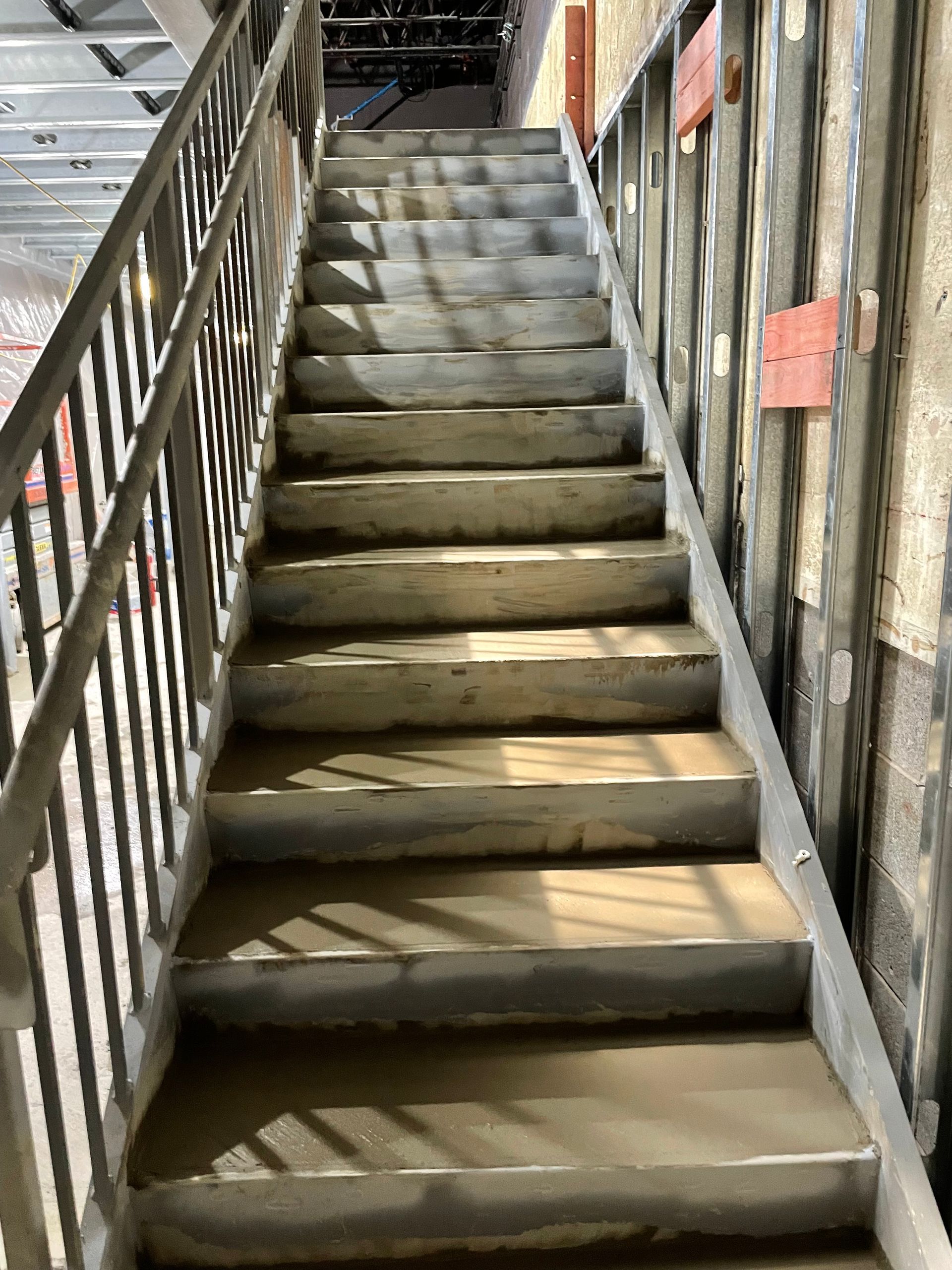 A set of stairs leading up to a building with a metal railing.