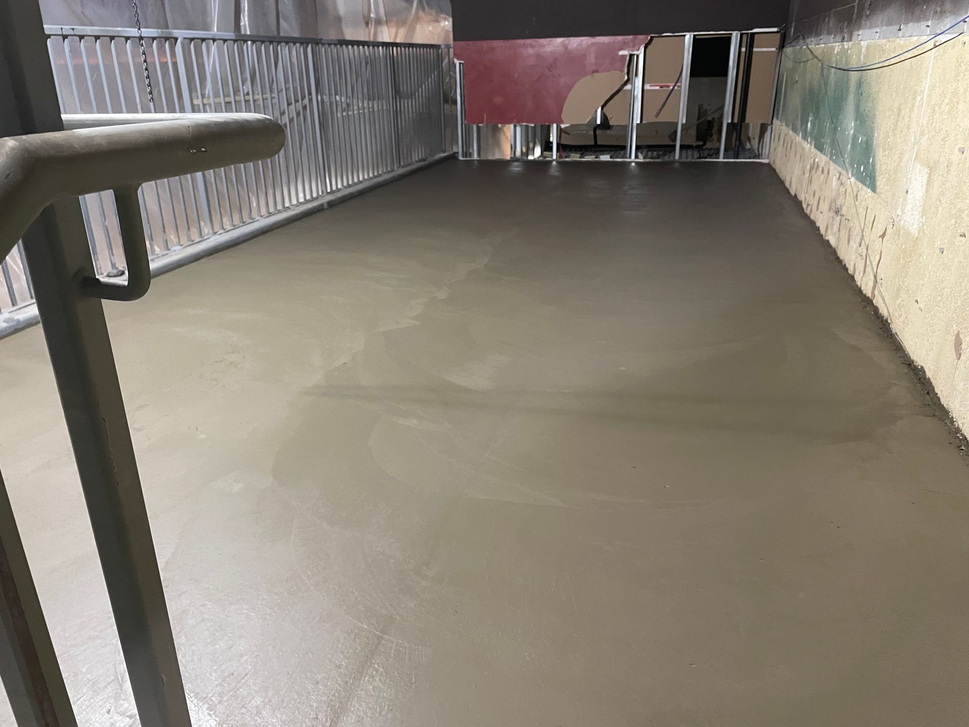 A concrete floor is being poured in a room with stairs.
