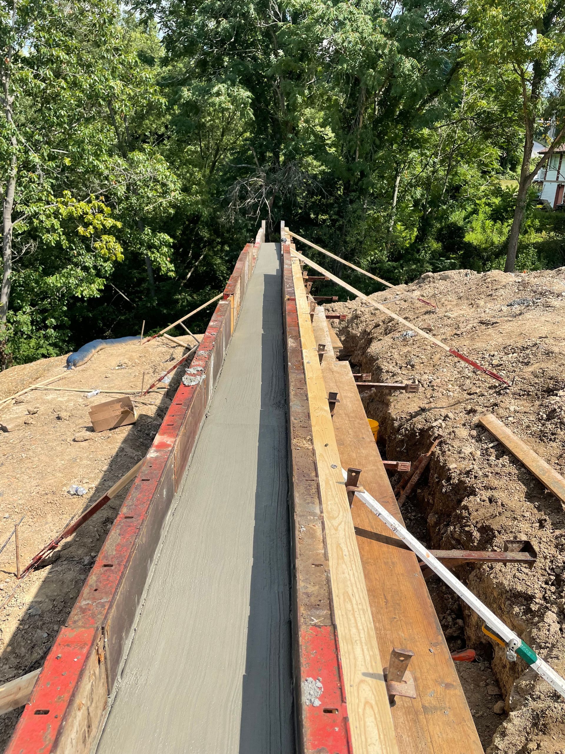 A concrete wall is being built in a field with trees in the background.