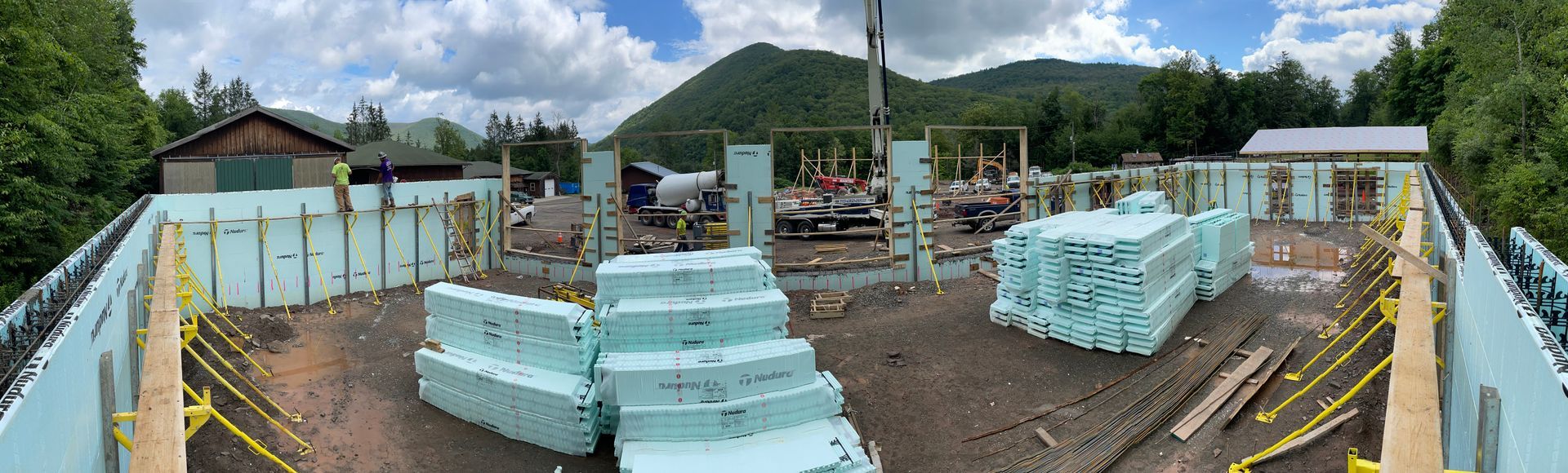 A panoramic view of a building under construction with a crane in the background.