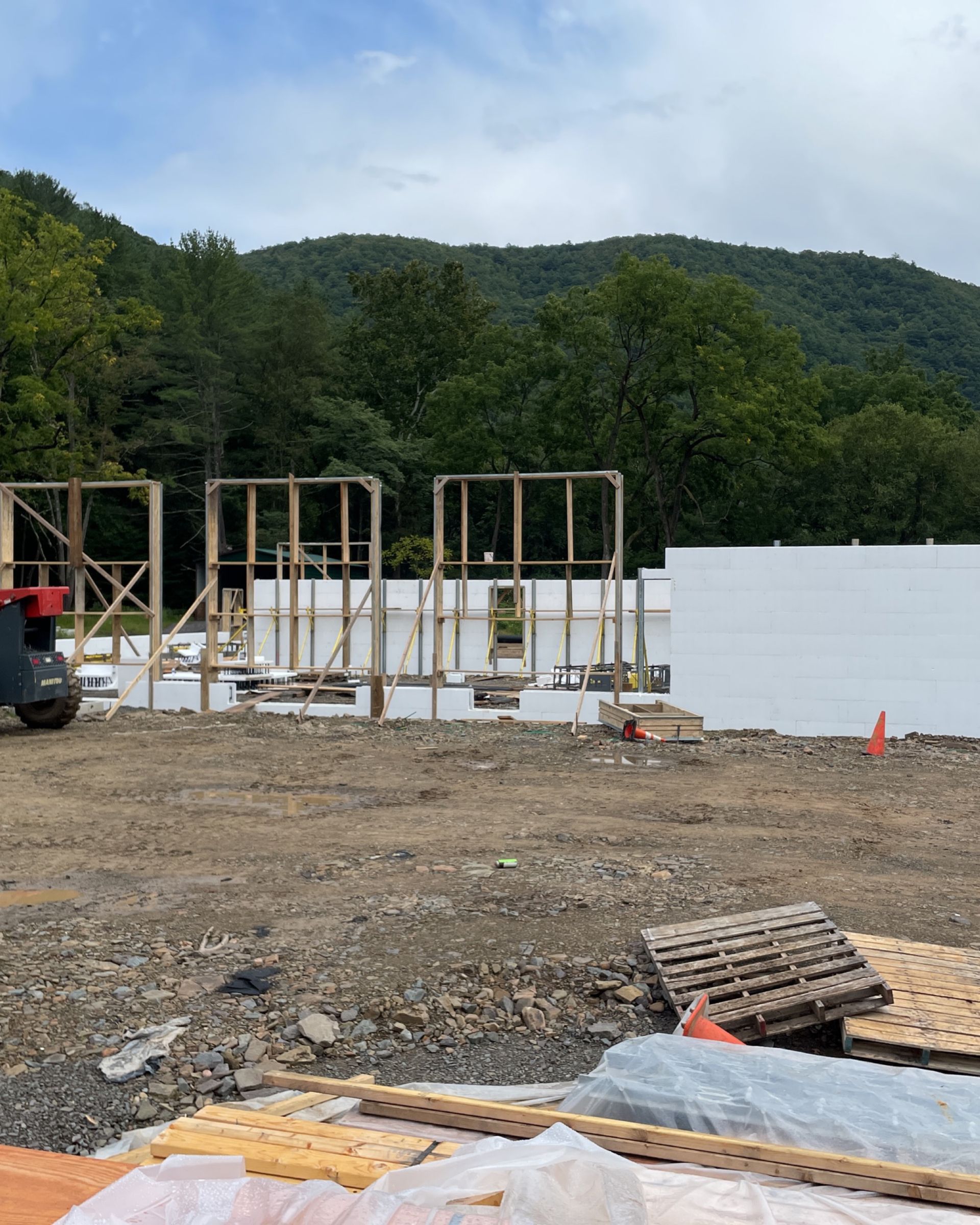 A building is being built in a field with mountains in the background