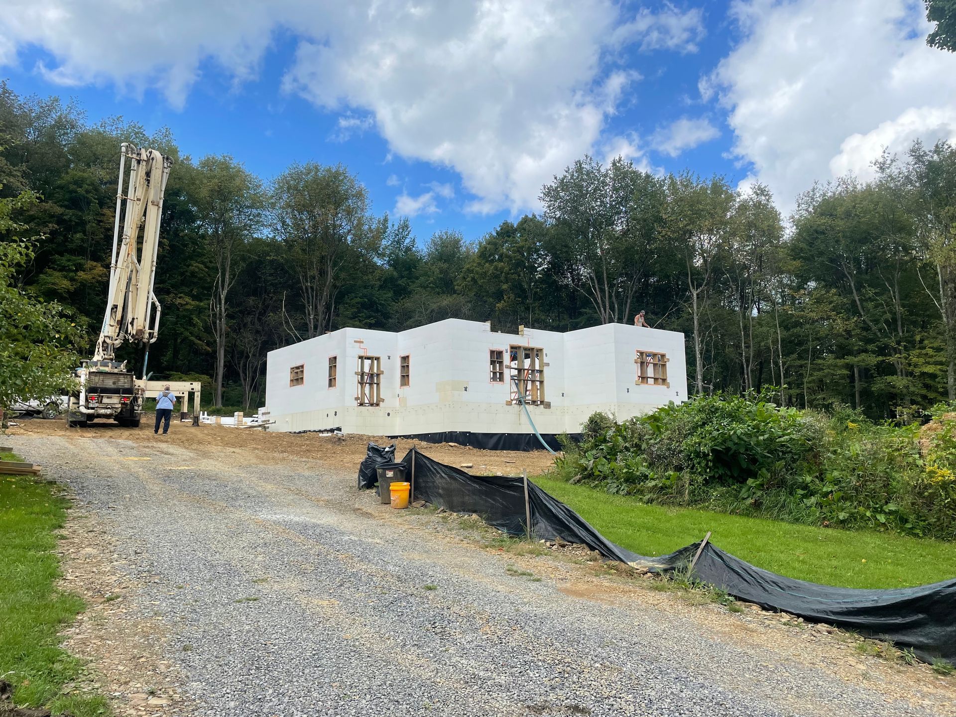 A large white house is being built in the middle of a forest.