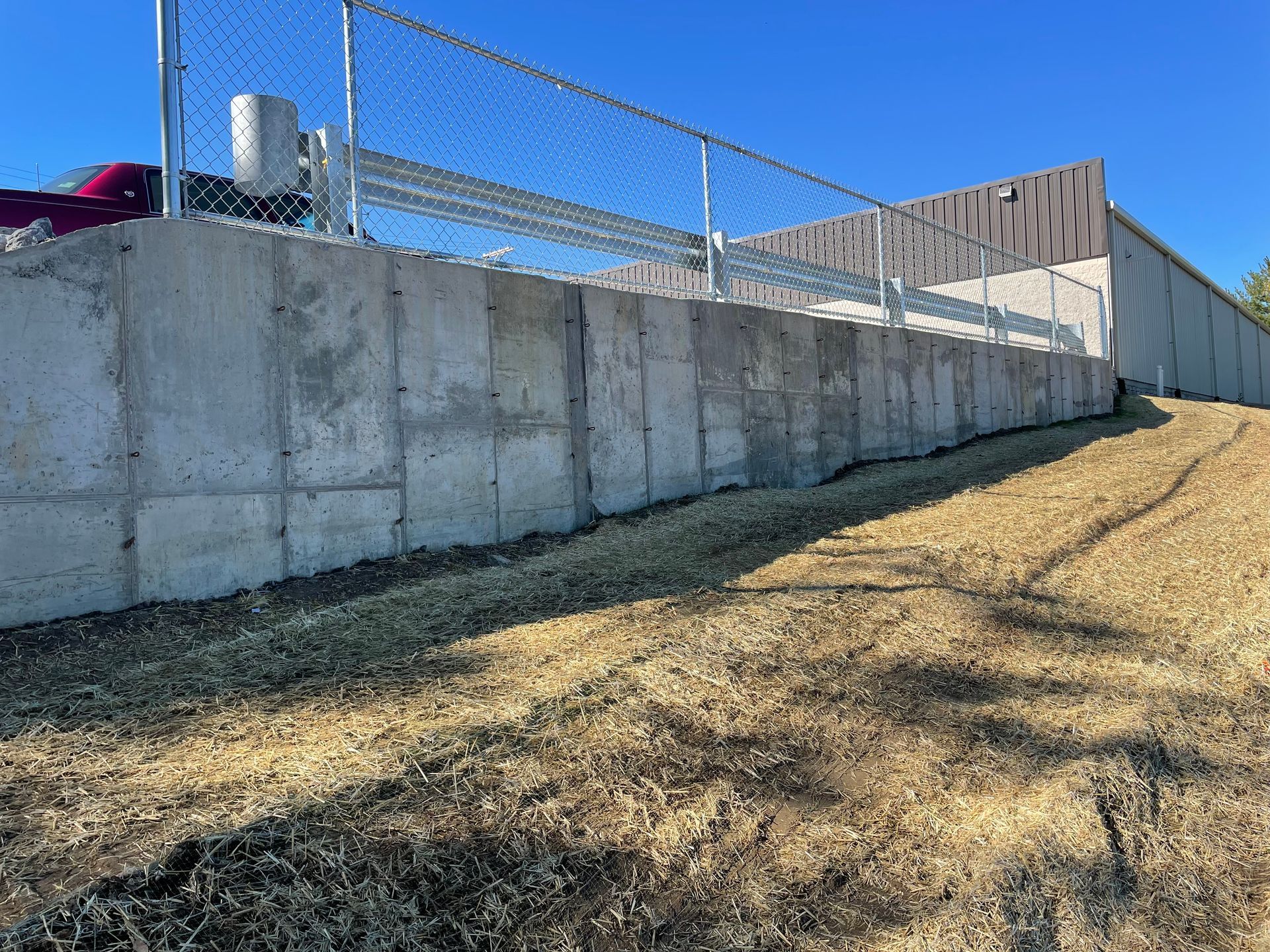A large concrete wall with a chain link fence surrounding it.