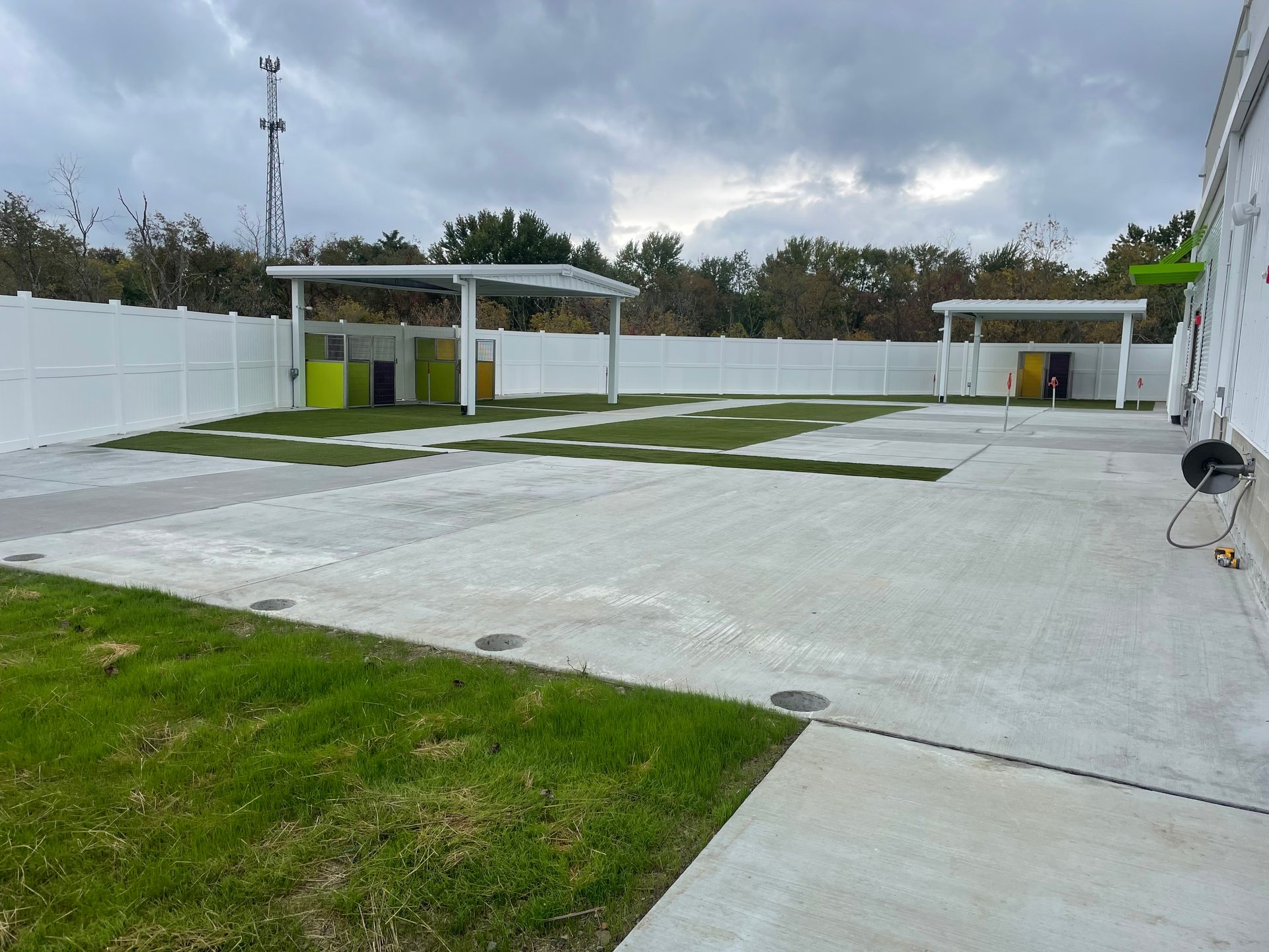 A large concrete area with grass and a white fence