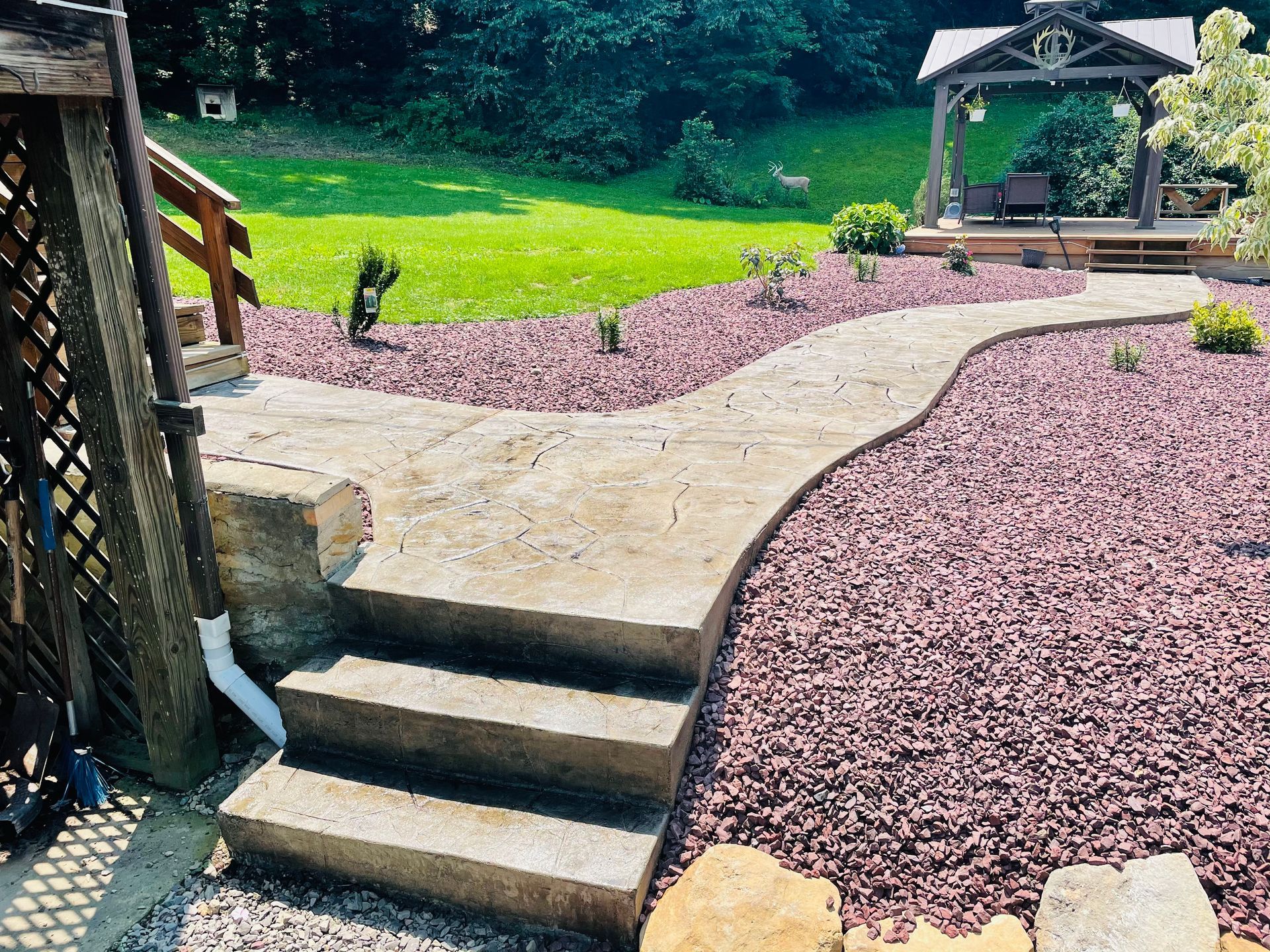 A concrete walkway leading to a gazebo in the backyard.