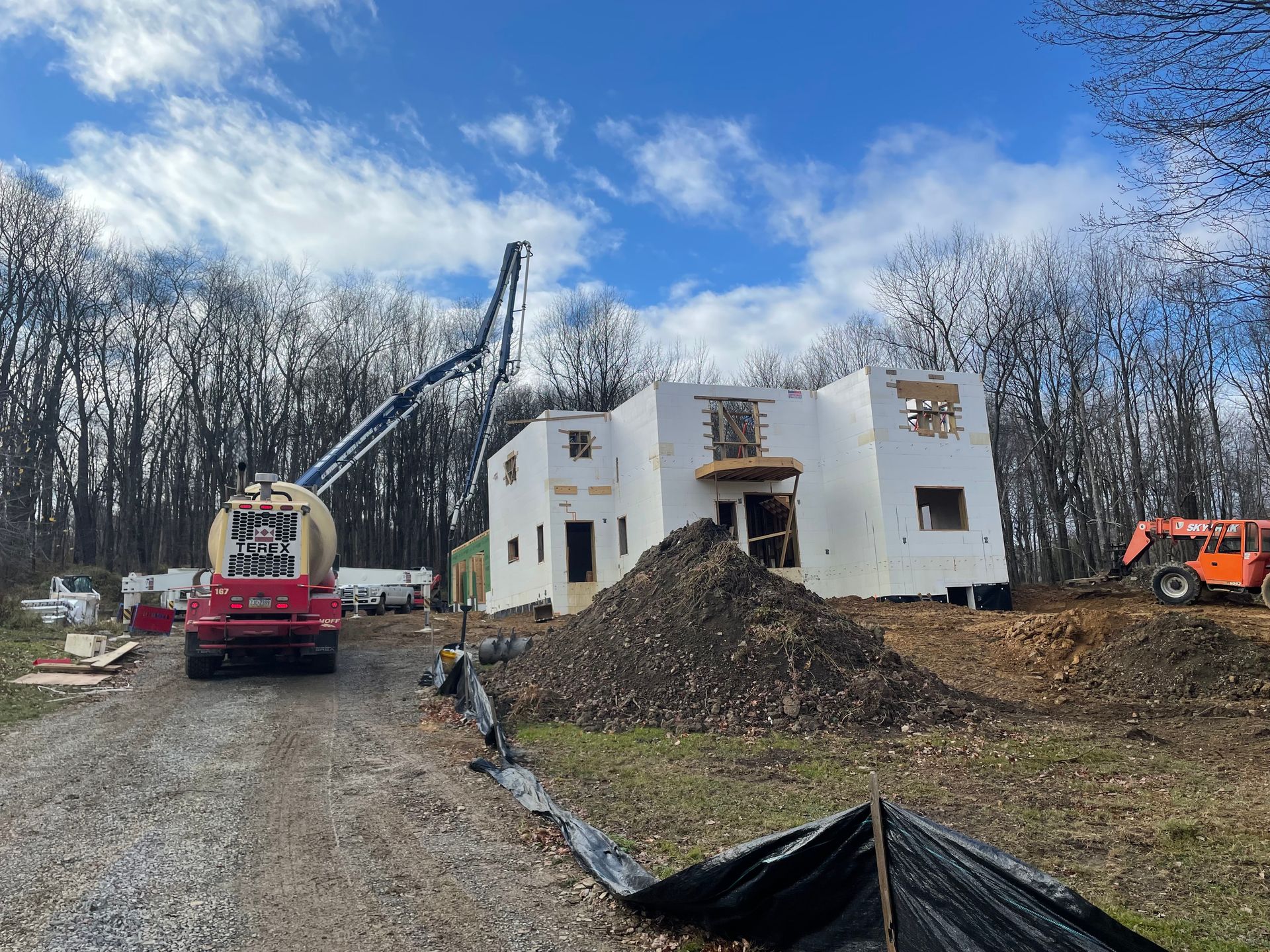 A large white house is being built in the middle of a forest.