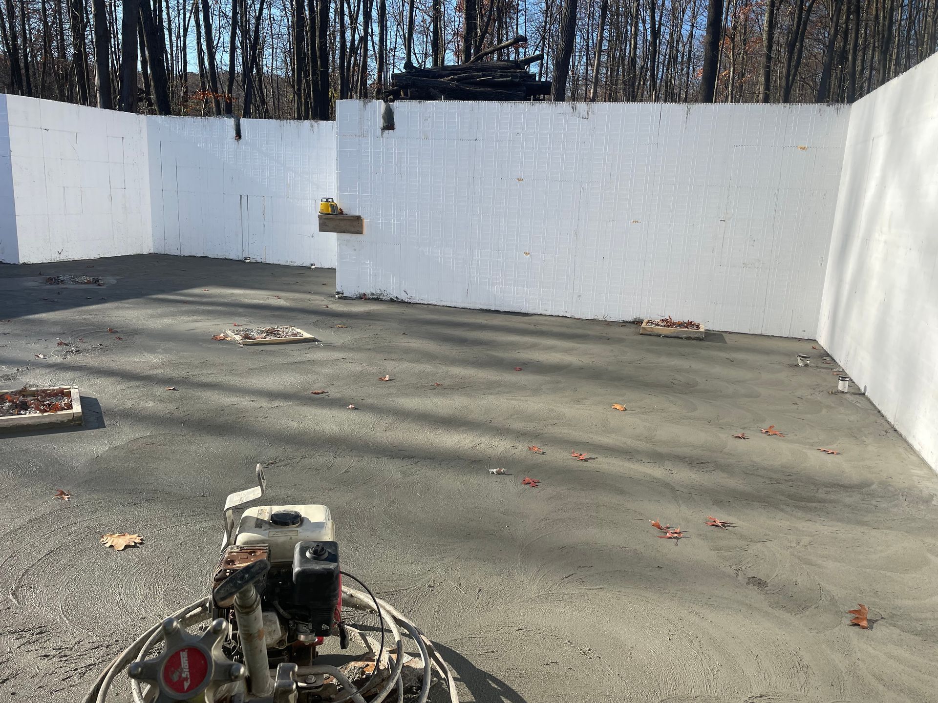 A machine is sitting on the ground in front of a white wall.