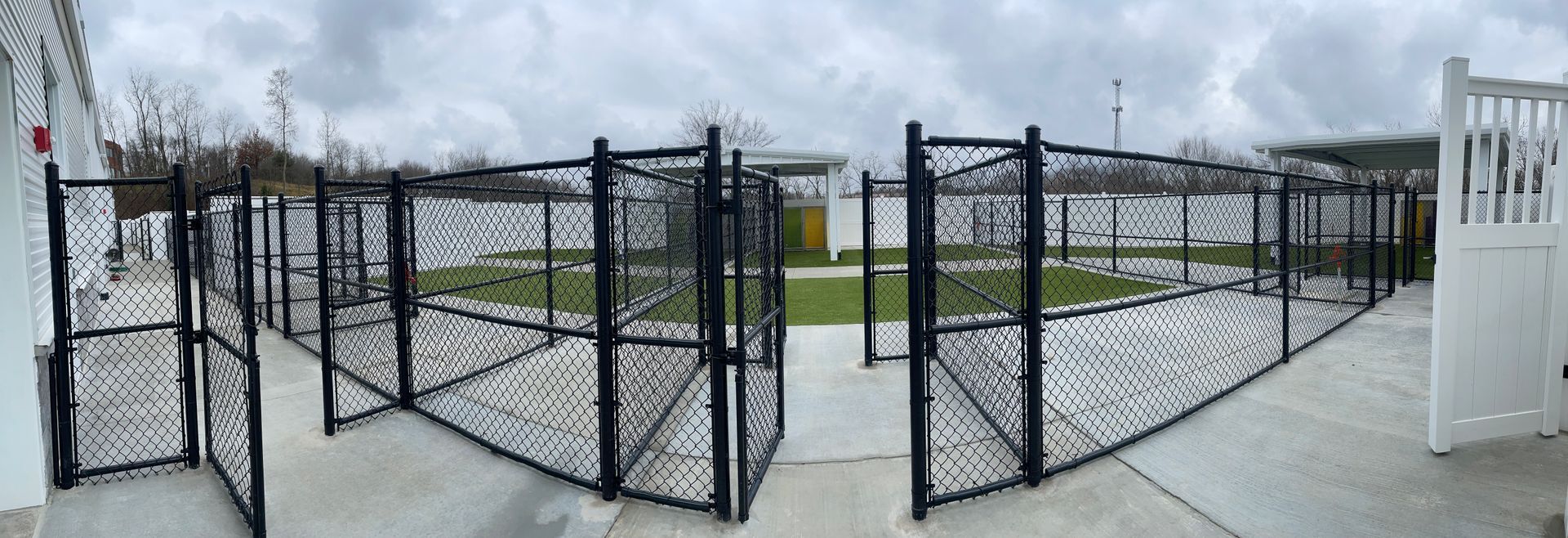 A black chain link fence is surrounding a concrete walkway.