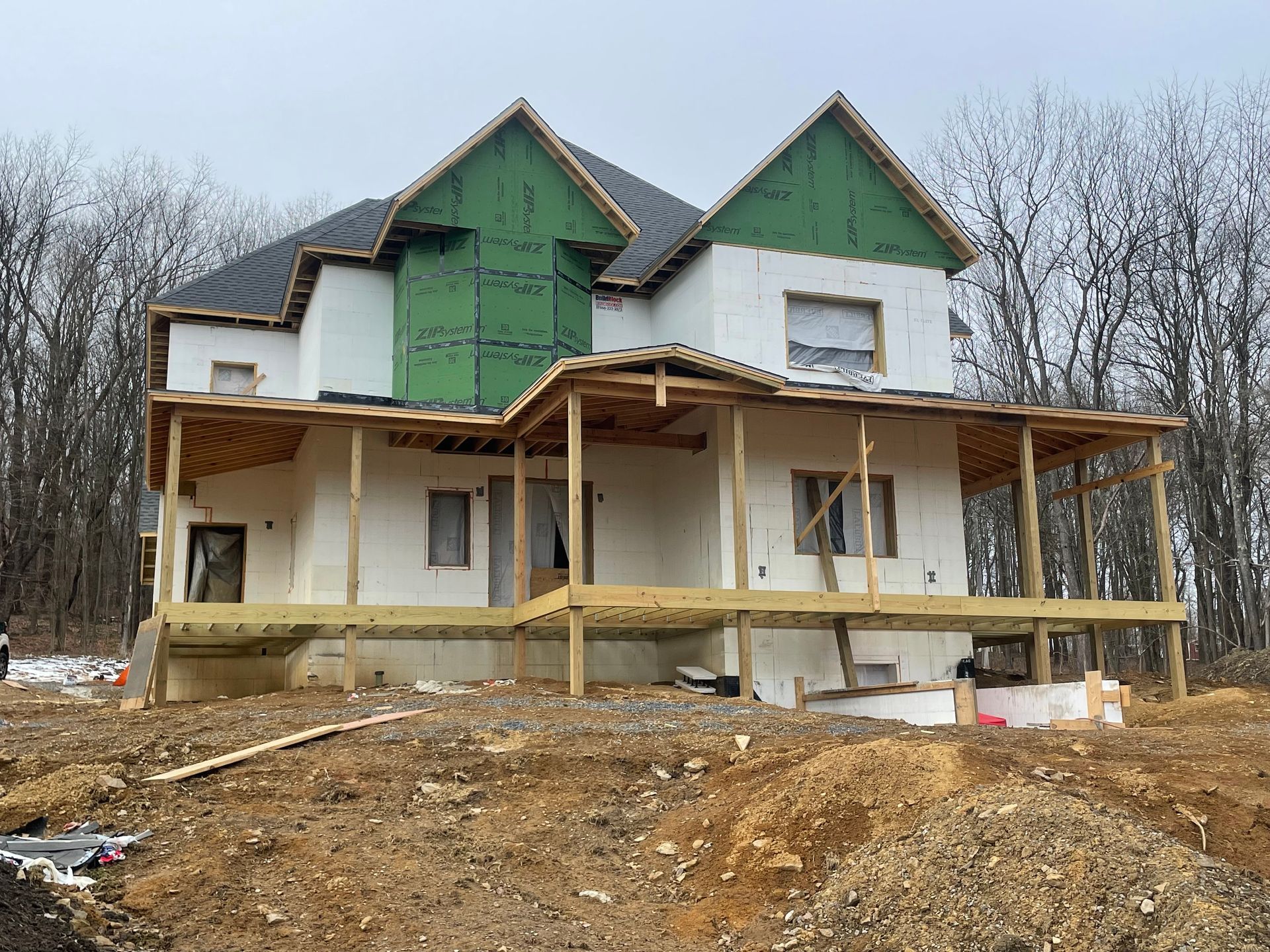 A large house is being built on top of a dirt hill.