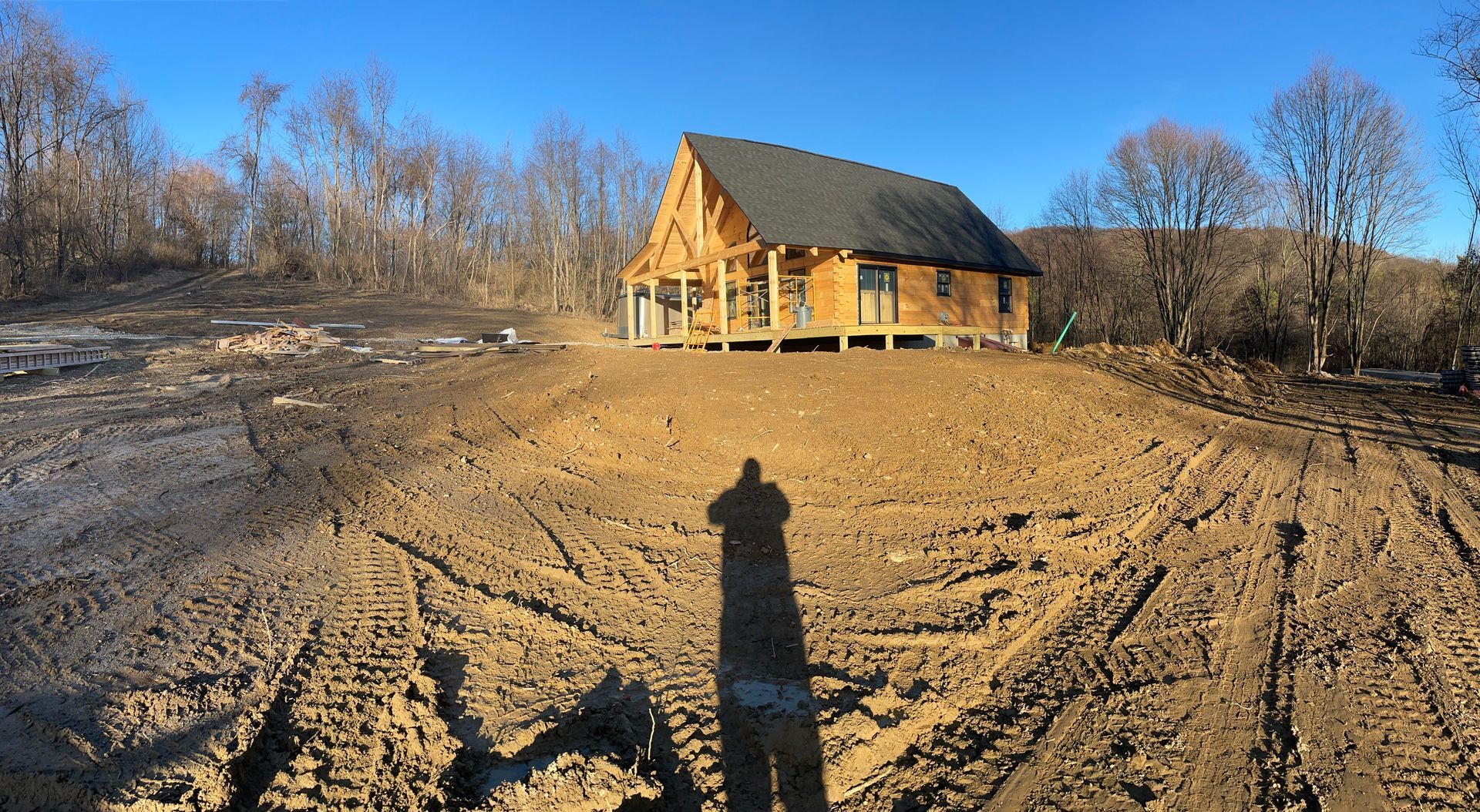 A log cabin is being built in the middle of a dirt field.