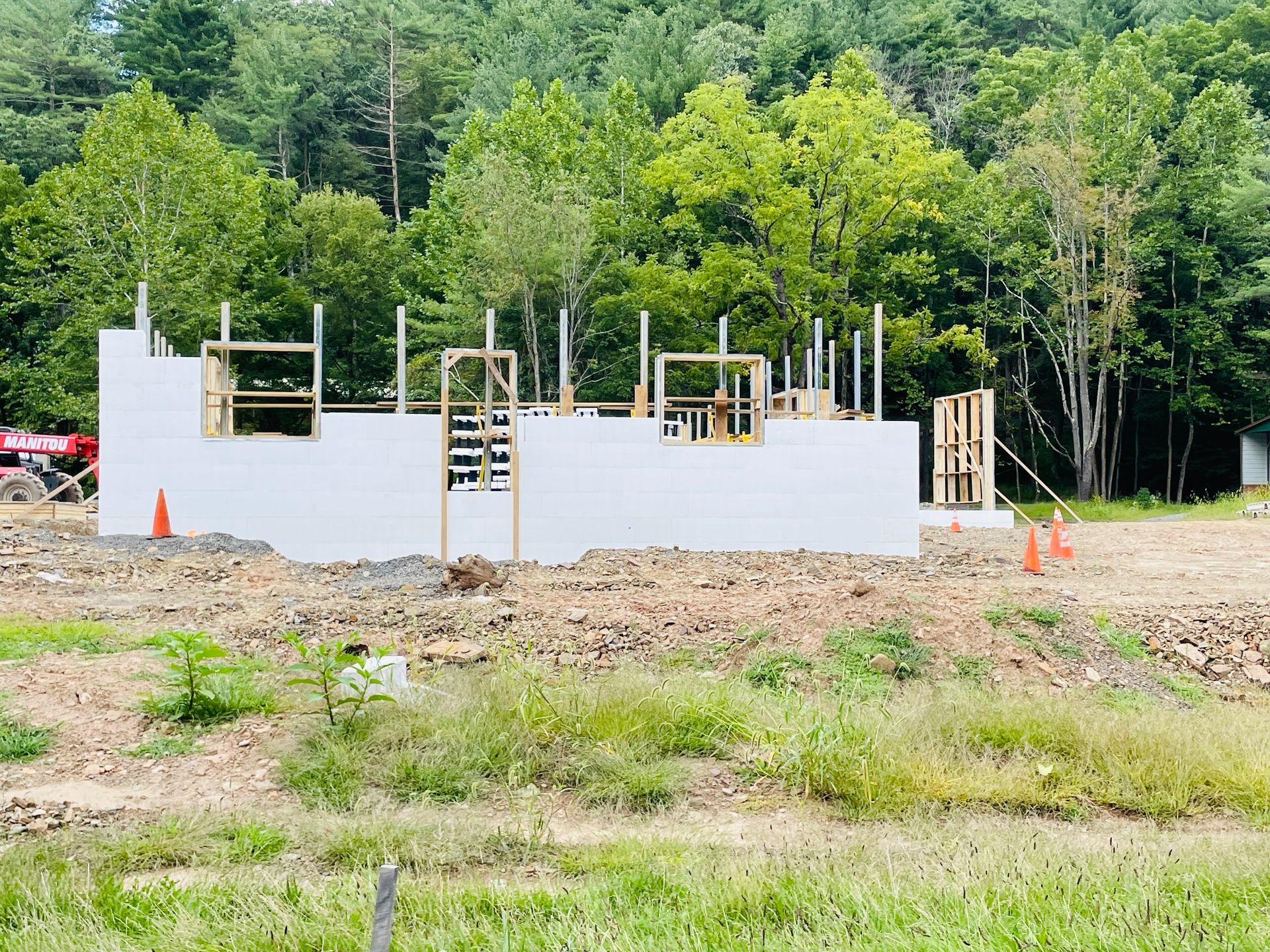 A house is being built in a field with trees in the background.