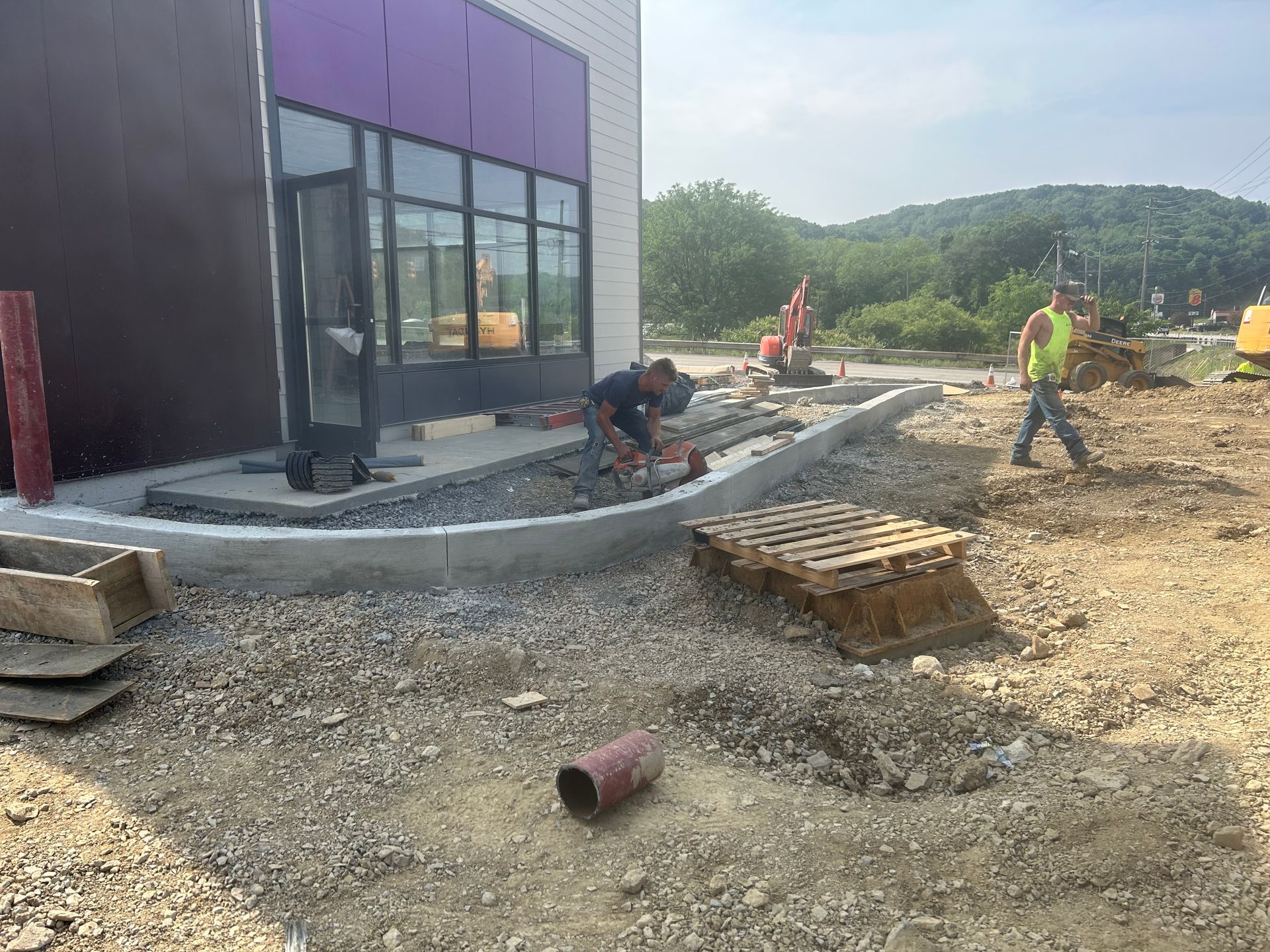 A group of construction workers are working on a sidewalk in front of a building.