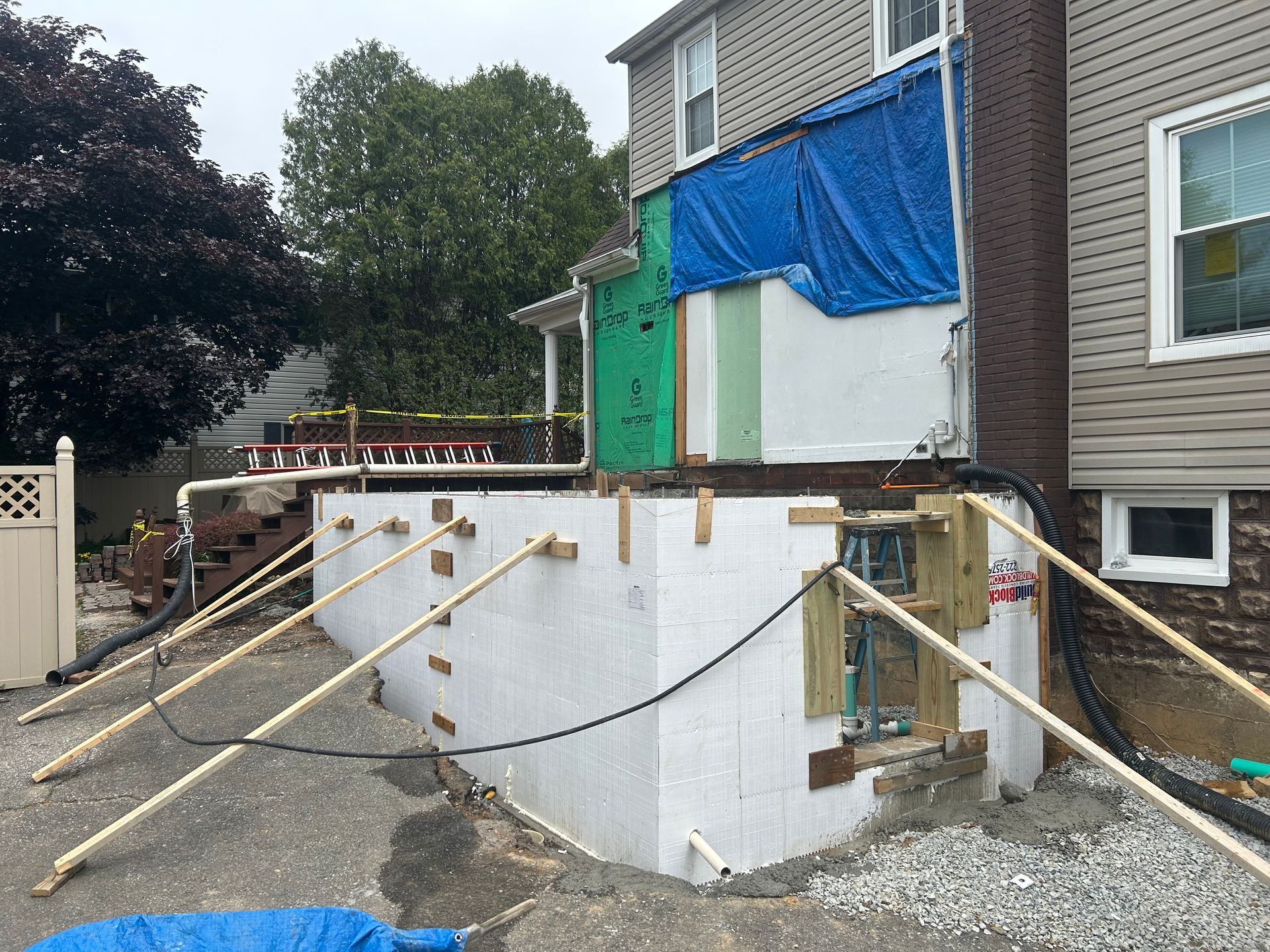 A house is being remodeled and a blue tarp is covering the side of the house.