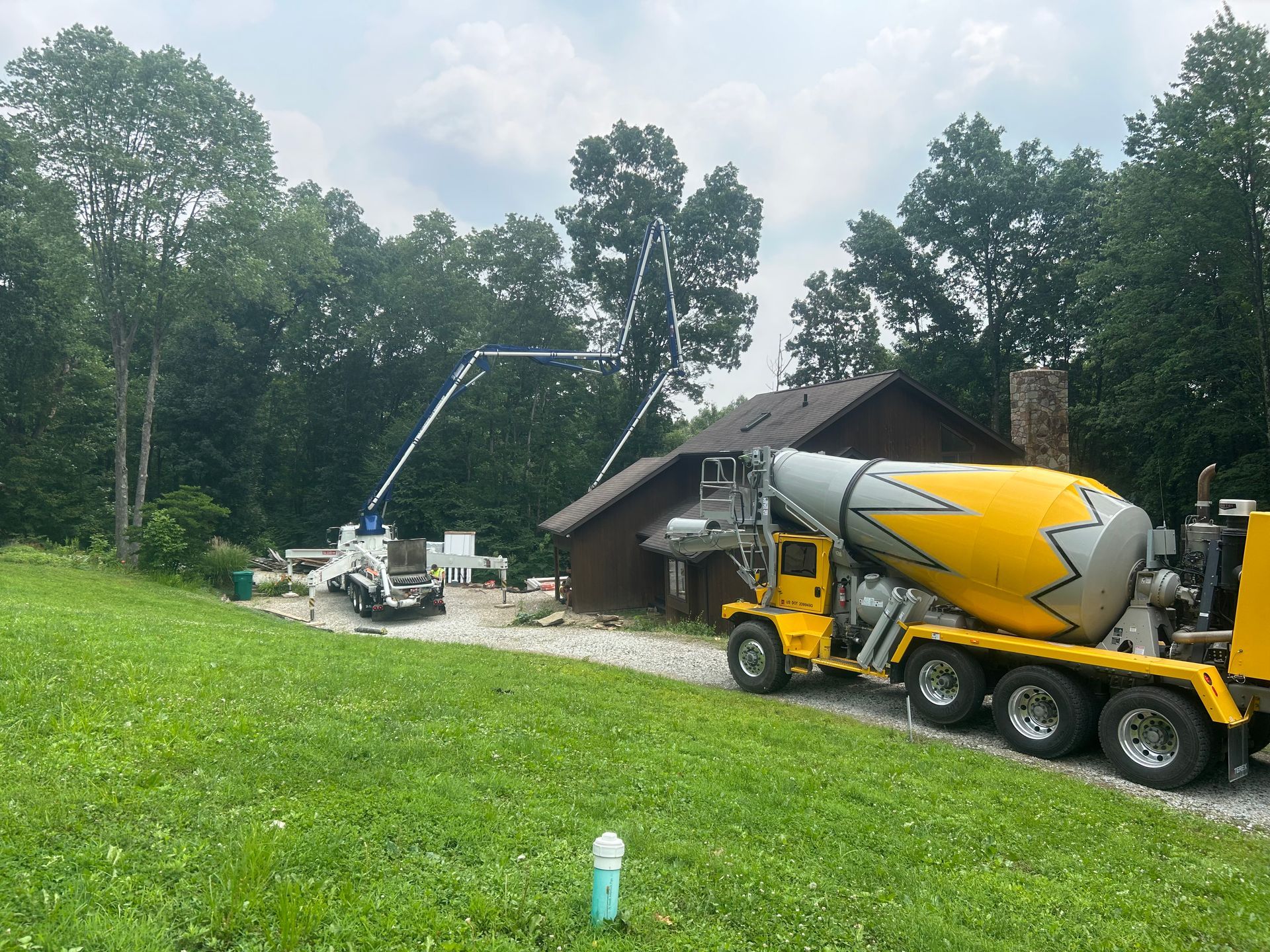 A yellow concrete mixer truck is parked in front of a house.