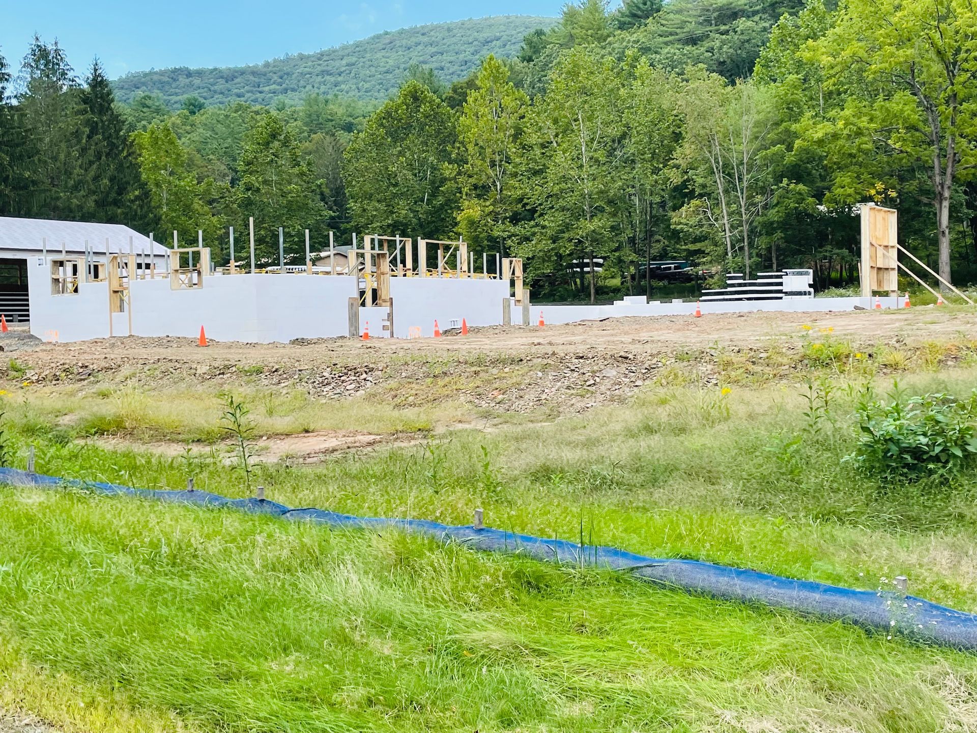 A large building is being built in the middle of a field surrounded by trees.