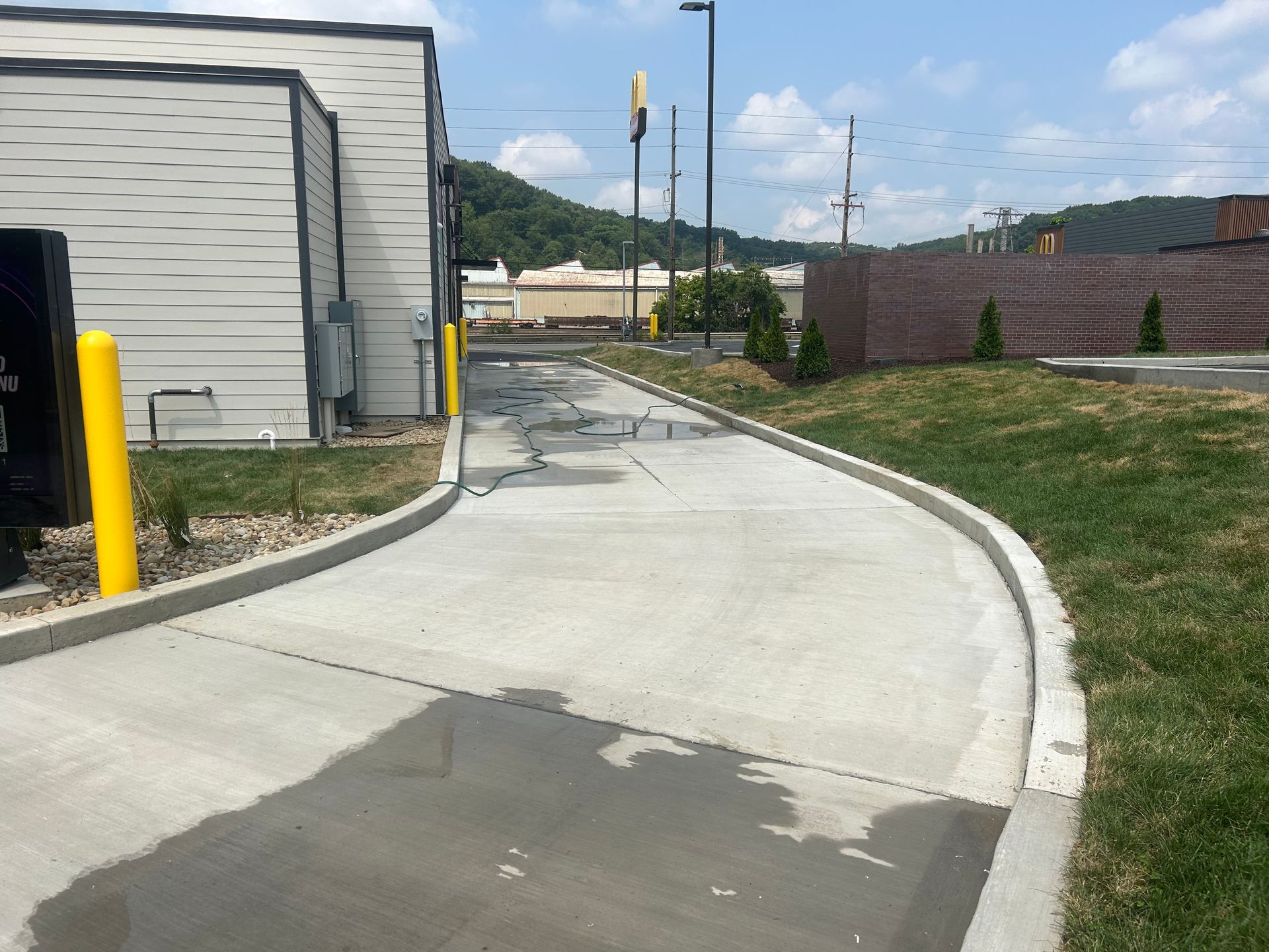 A concrete walkway with a yellow pole on the side of it