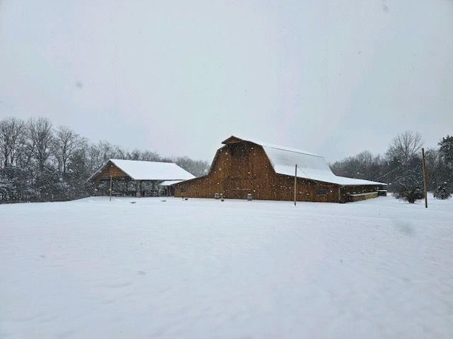 A large barn is sitting in the middle of a snow covered field.