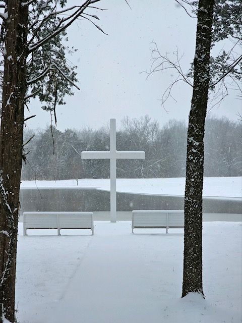 A white cross in the middle of a snowy field