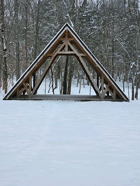 A wooden structure is sitting in the middle of a snow covered field.