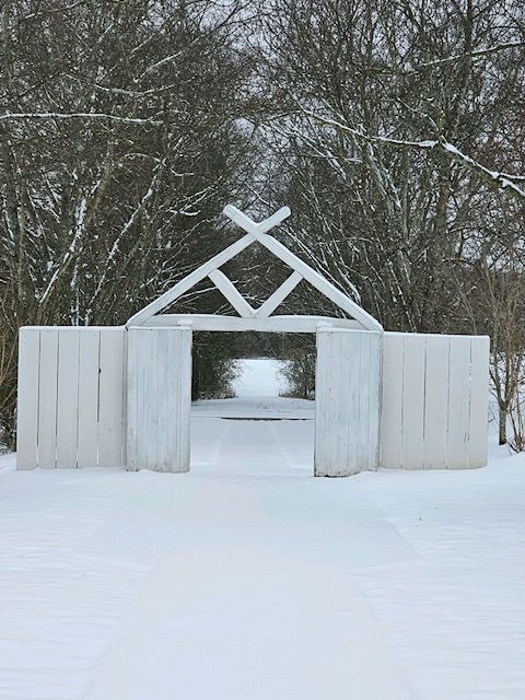 A white wooden structure in the middle of a snowy forest.