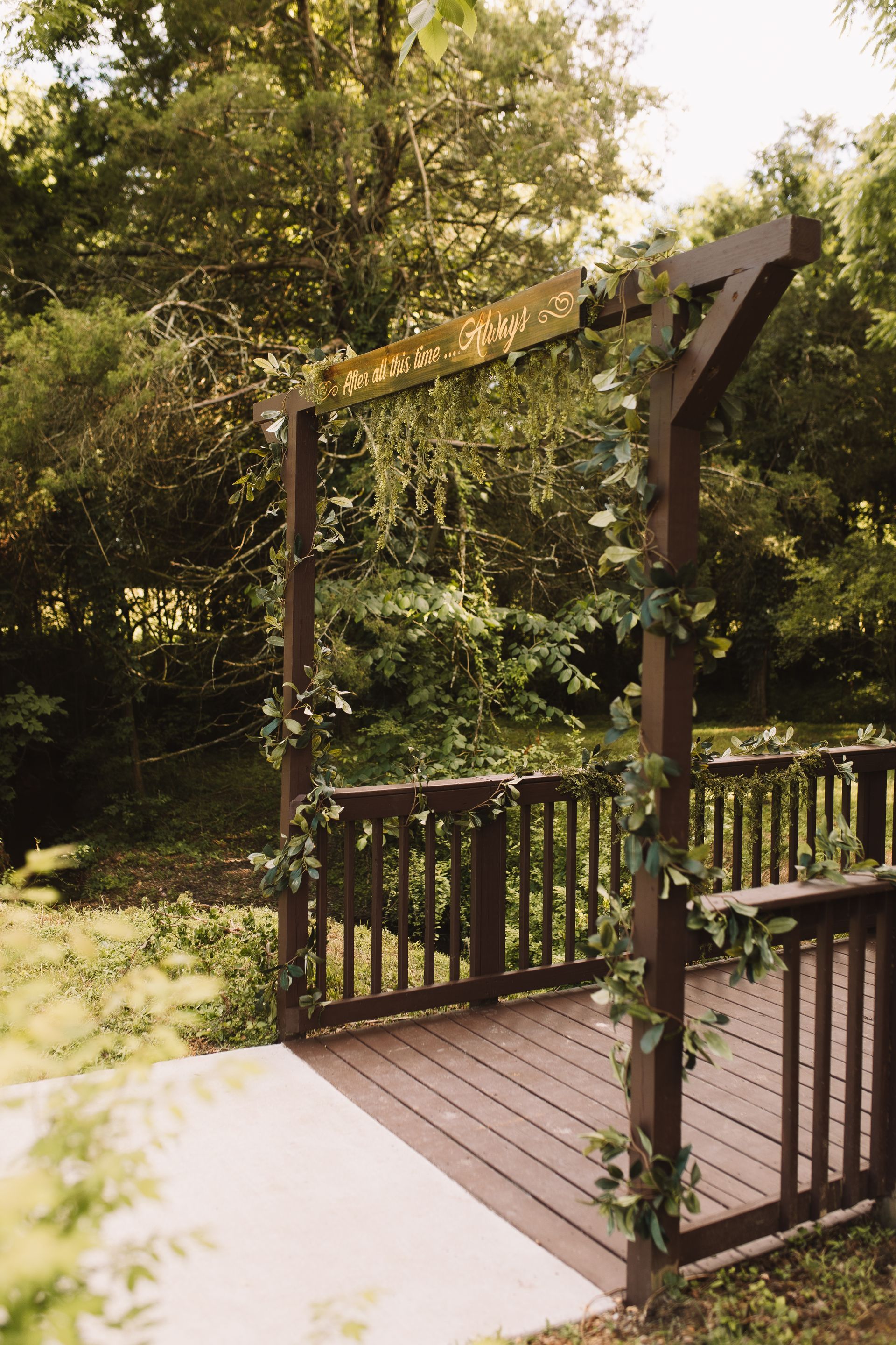 A wooden bridge with a wooden arch and vines hanging from it.