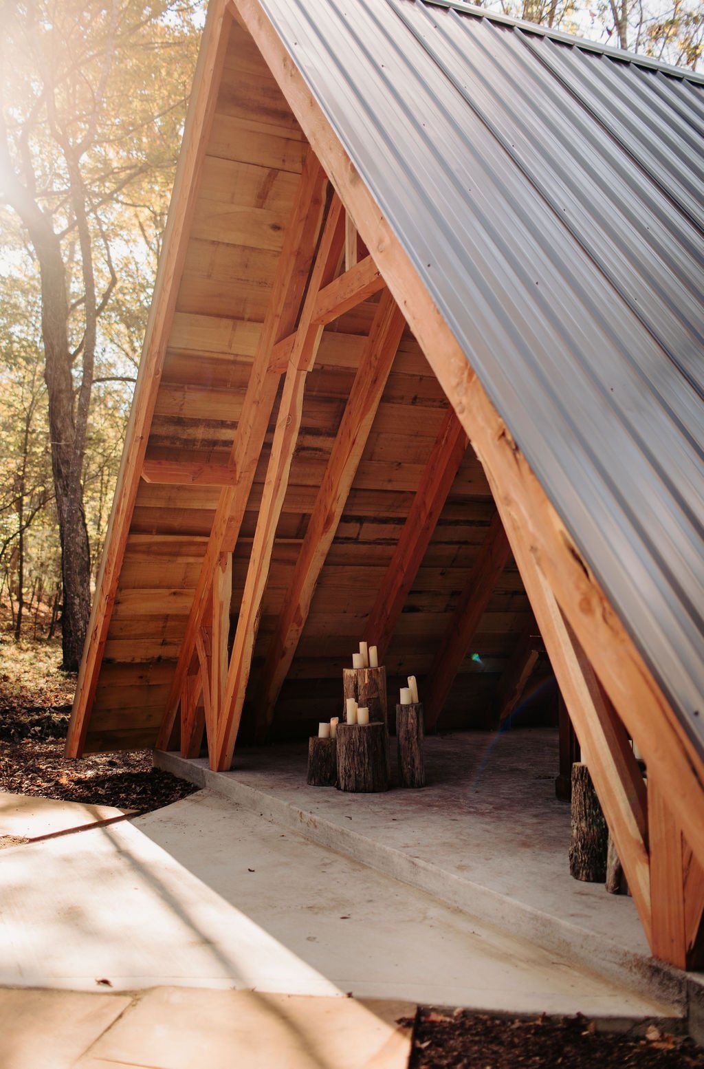 A wooden structure with a metal roof in the middle of a forest.