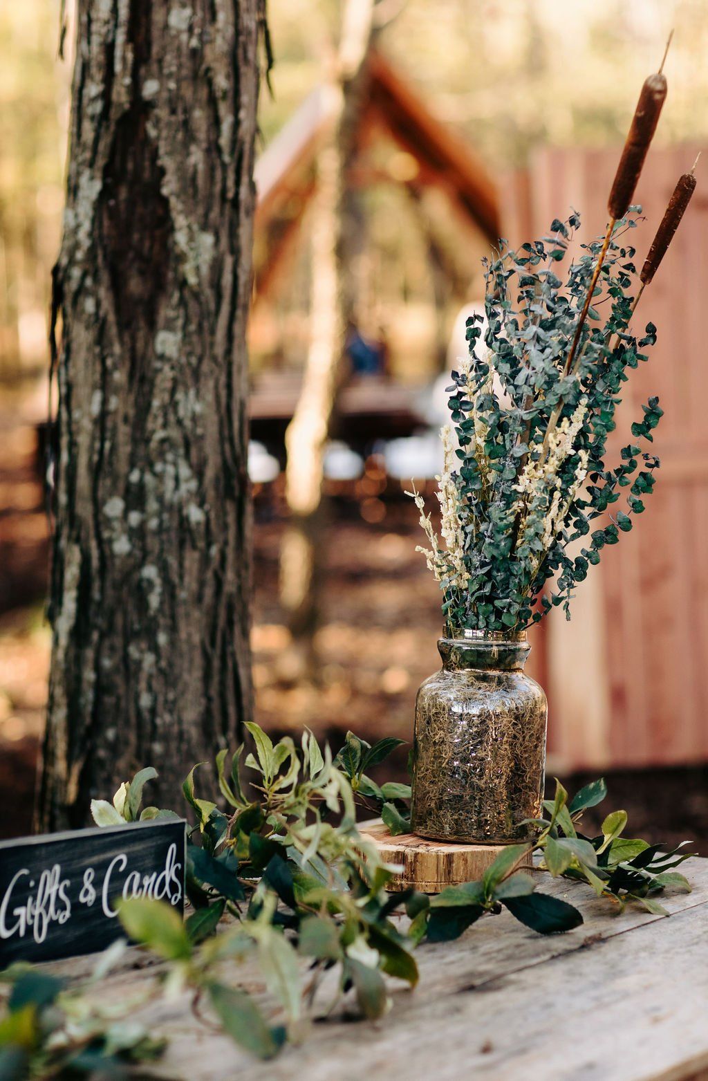 A vase of flowers is sitting on a wooden table next to a tree.