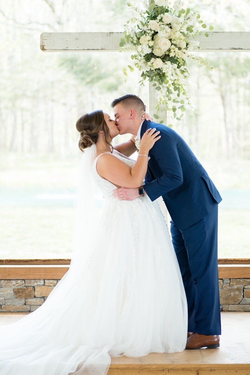 A bride and groom are kissing at their wedding ceremony.