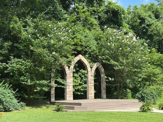 A stone archway surrounded by trees in a park