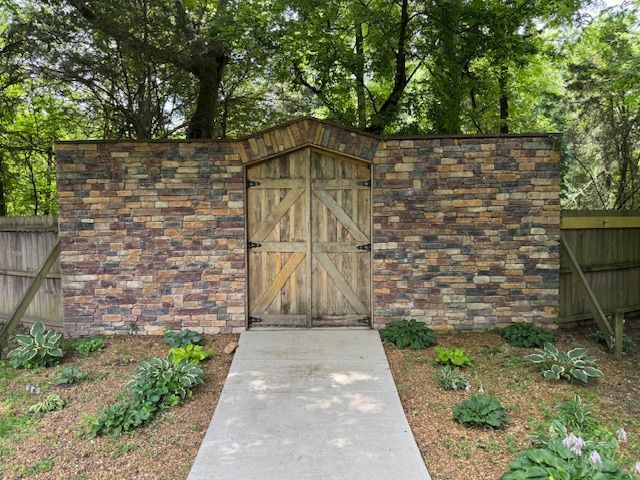 A brick wall with a wooden gate in the middle of it