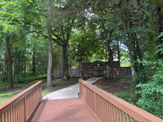 A wooden bridge leading to a fence in the middle of a forest.
