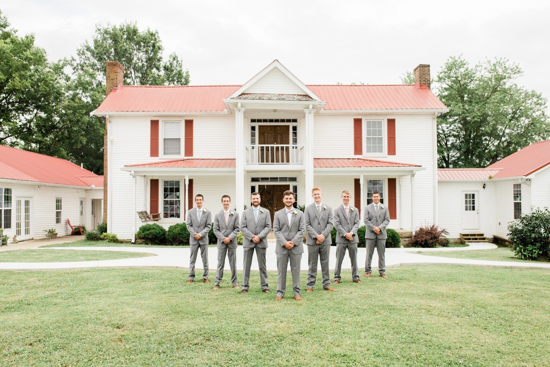 A group of men in suits are standing in front of a large white house.