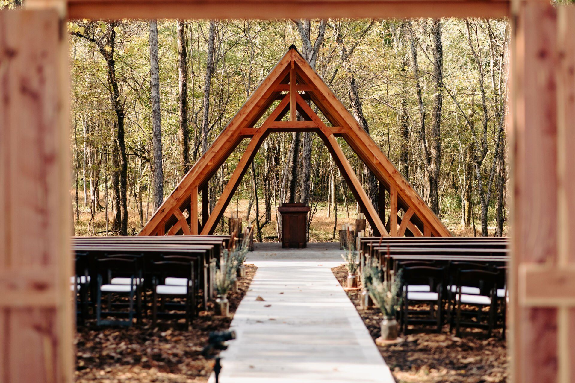 A wooden archway leading to a wedding ceremony in the woods.