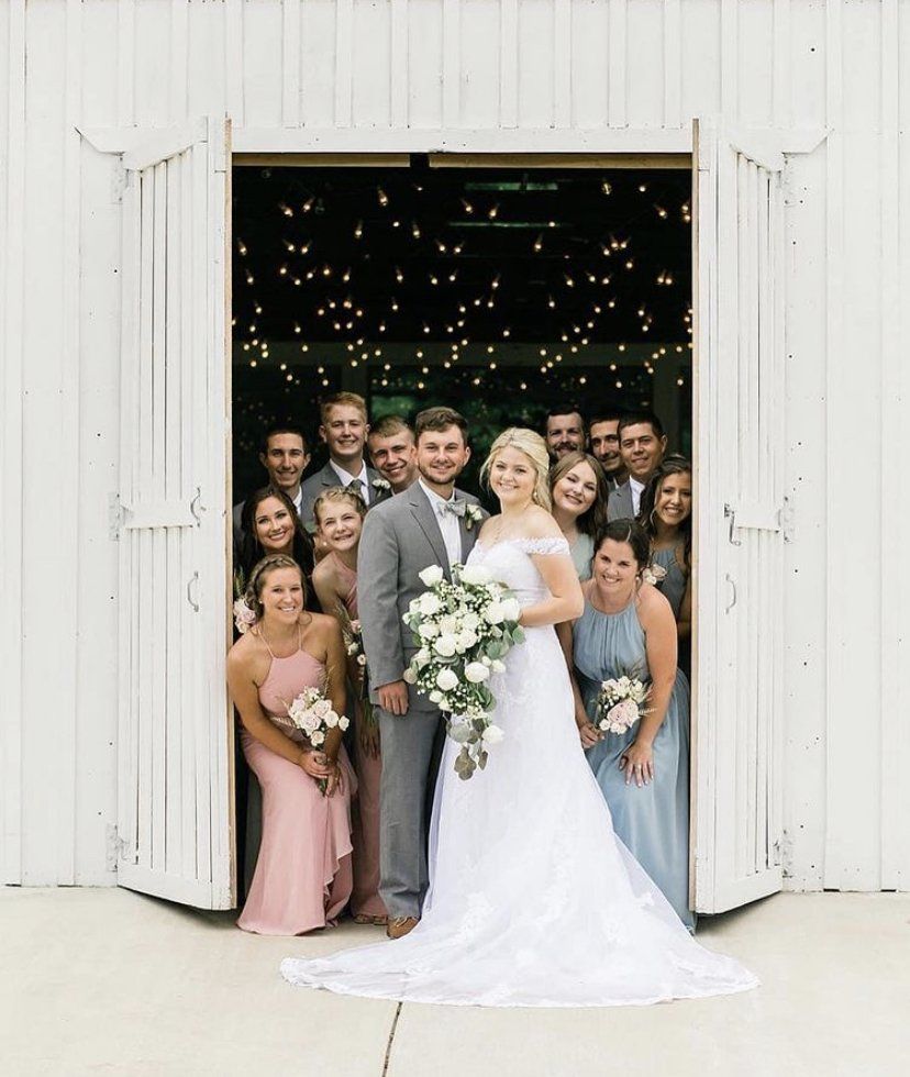 A bride and groom are posing for a picture with their wedding party.