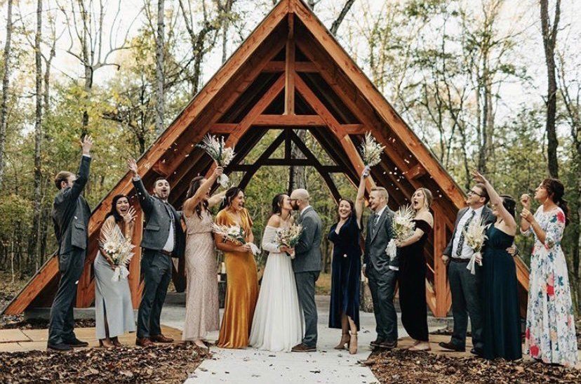 A group of people are standing in front of a wooden structure.